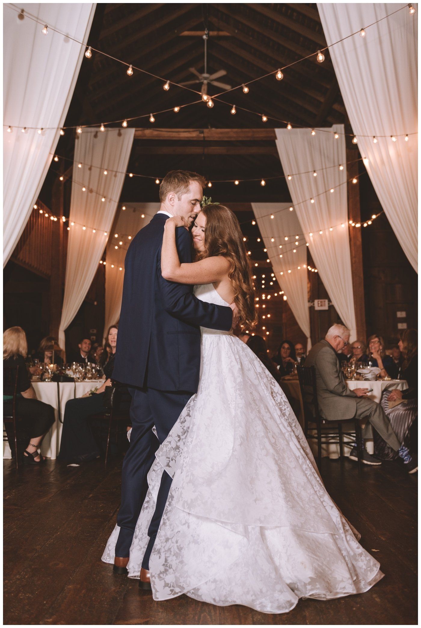 Bride and groom share a kiss on a decorated wedding dance floor under draped lights