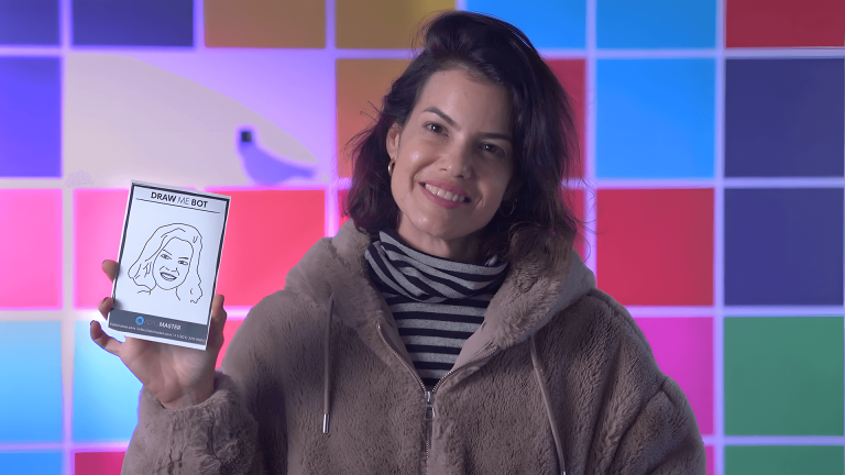 Smiling woman holds up a phone against a colorful tiled background.