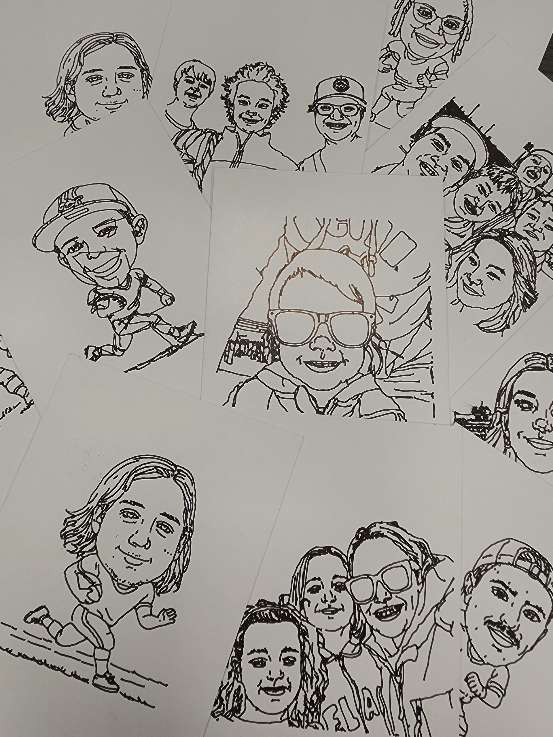 Black-and-white collage of hand-drawn cartoon faces and a central sketch on paper