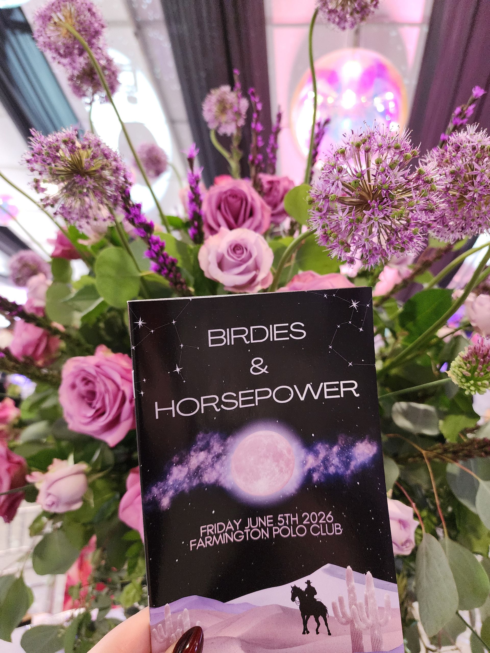 Floral bouquet with pink roses and a black “Brides & Horsepower” sign at a wedding display