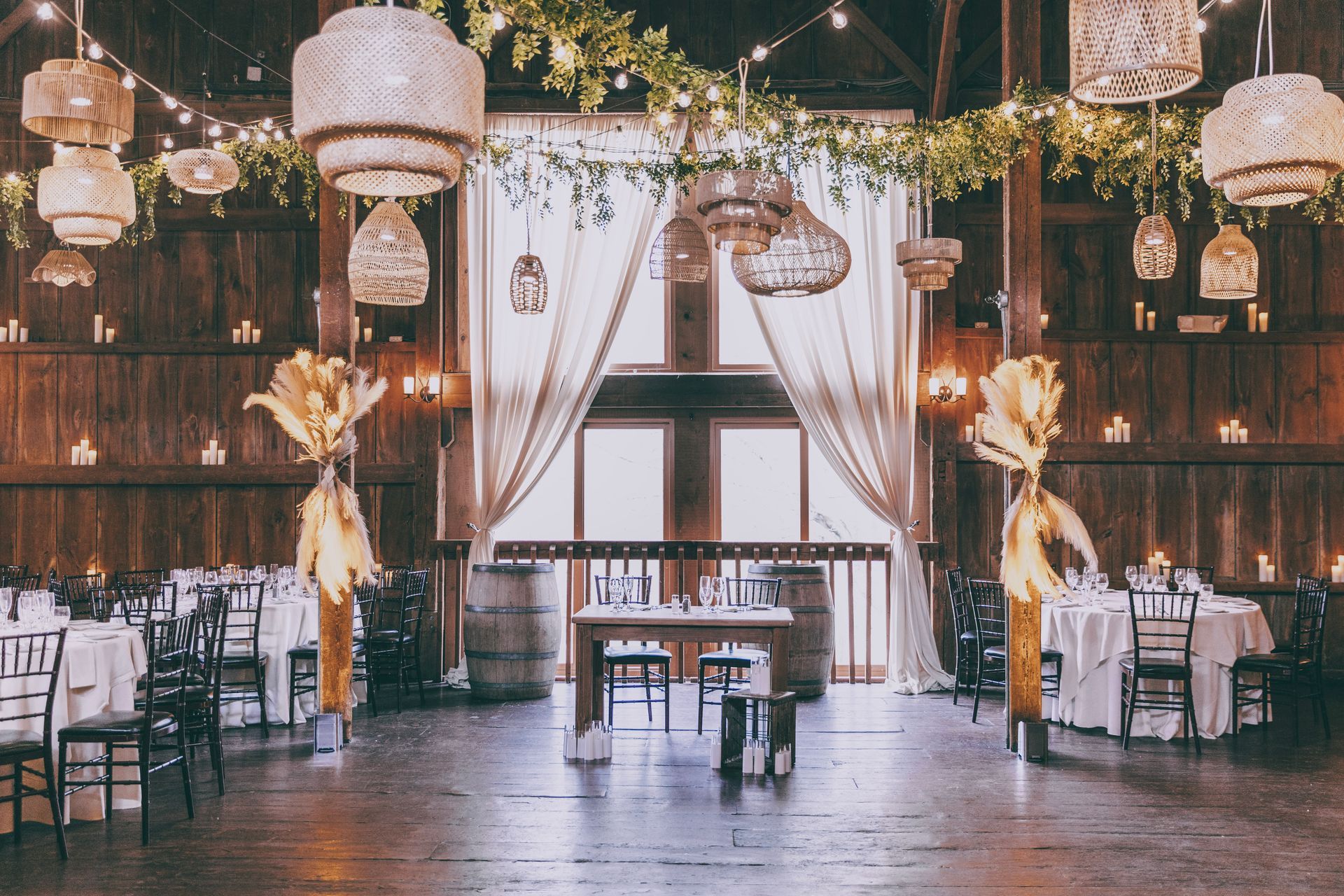 Elegant wedding reception hall with hanging lanterns, draped curtains, and warmly lit tables