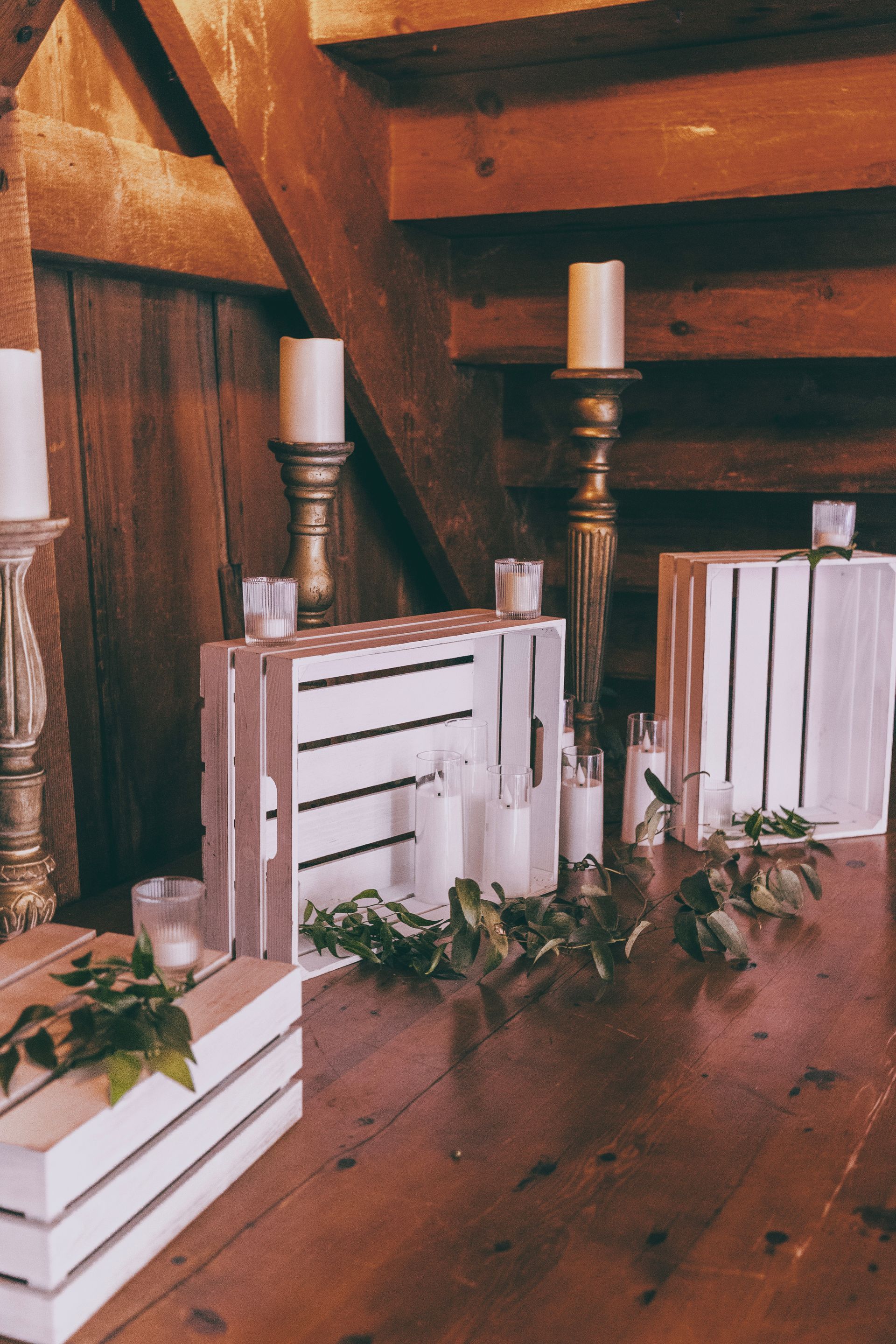 Wooden crate decor with white candles, books, and greenery on a stair landing