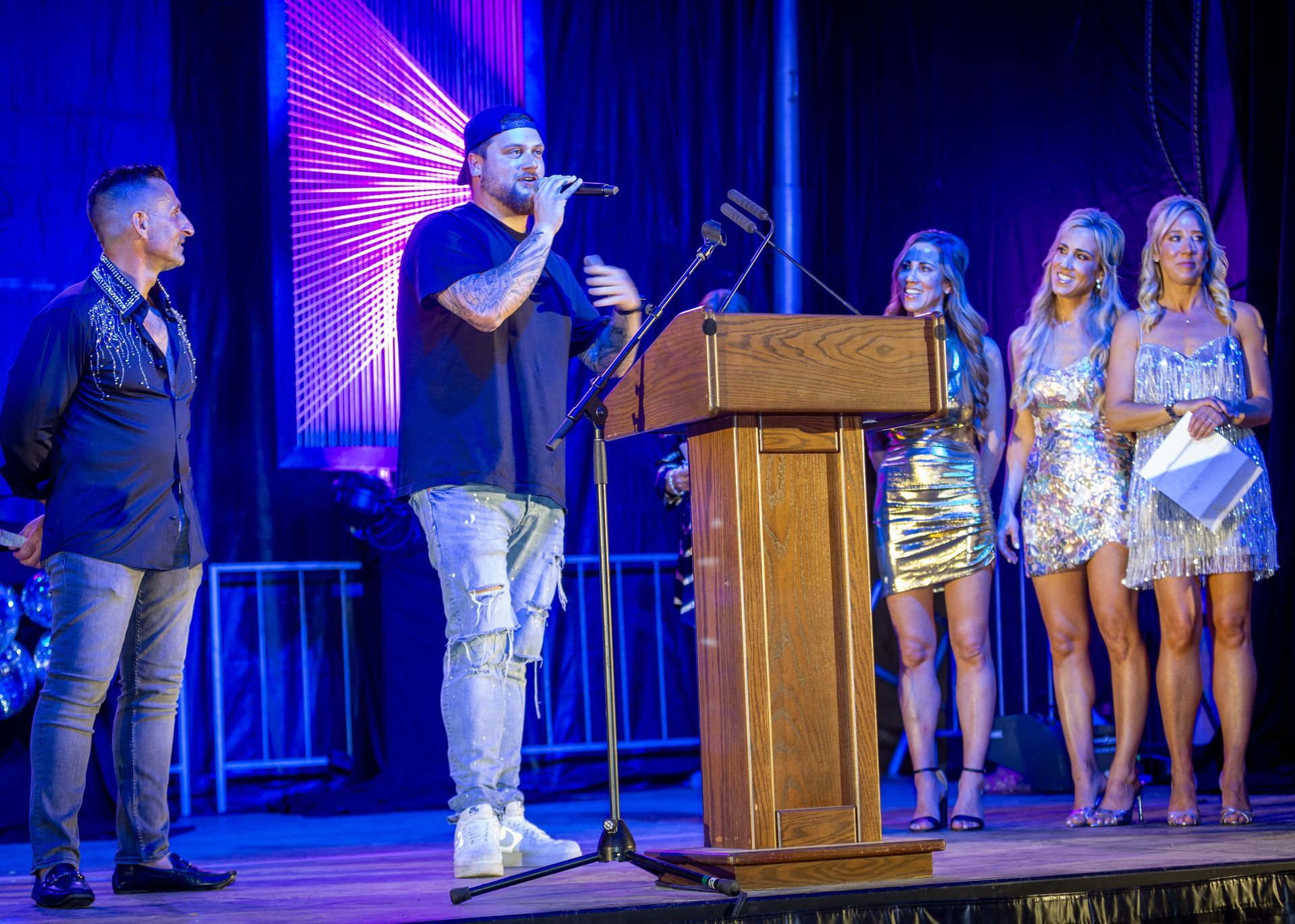 People on a stage during an award ceremony, with a speaker at a podium and performers standing beside him.