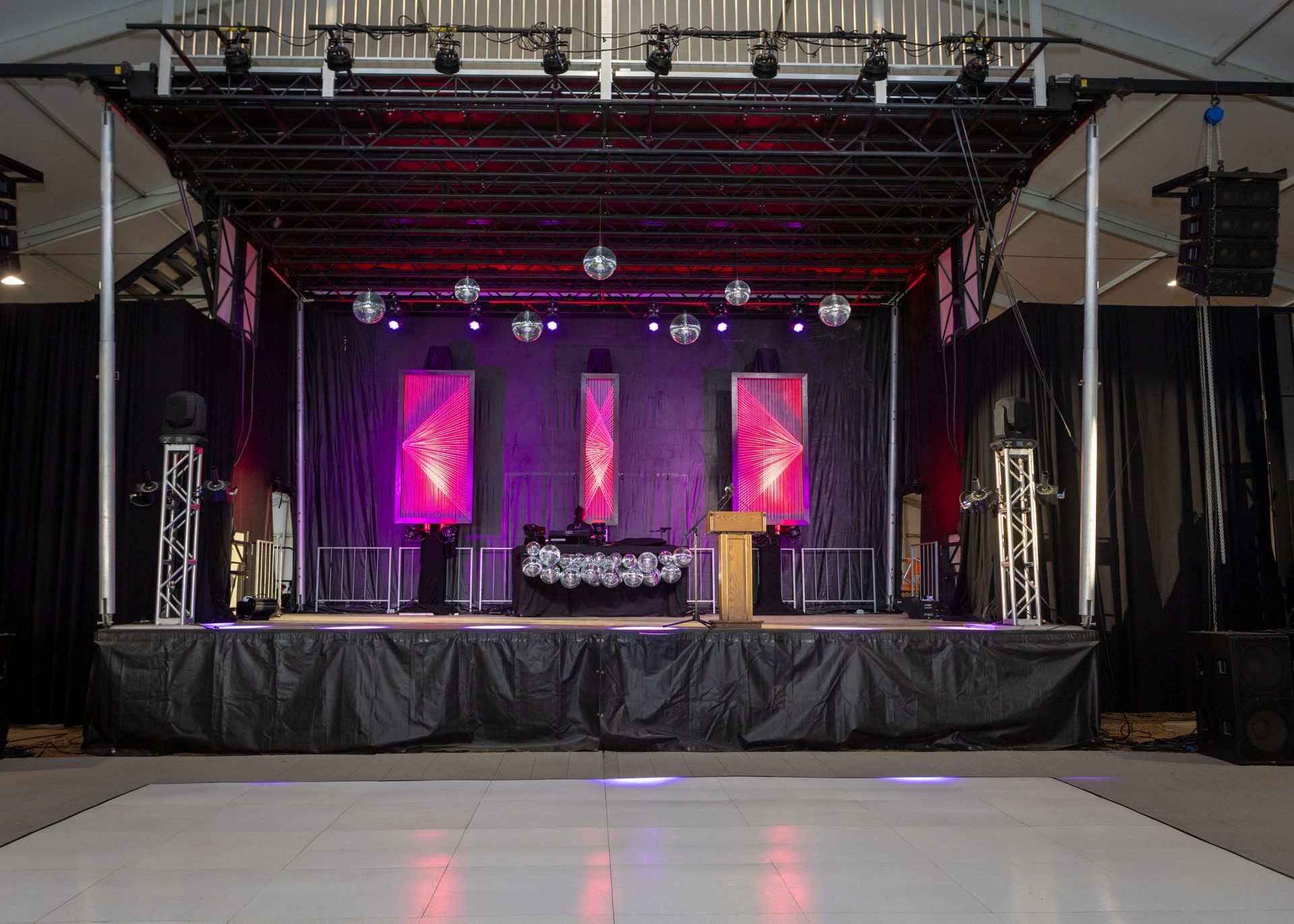 Empty indoor stage with purple lighting, three glowing panels, speakers, and a reflective dance floor