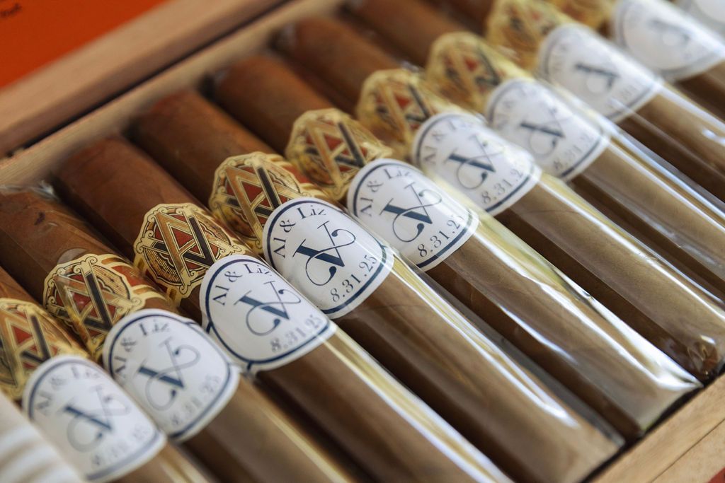 Tray of cigars wrapped in clear plastic with white labels, arranged in a wooden box