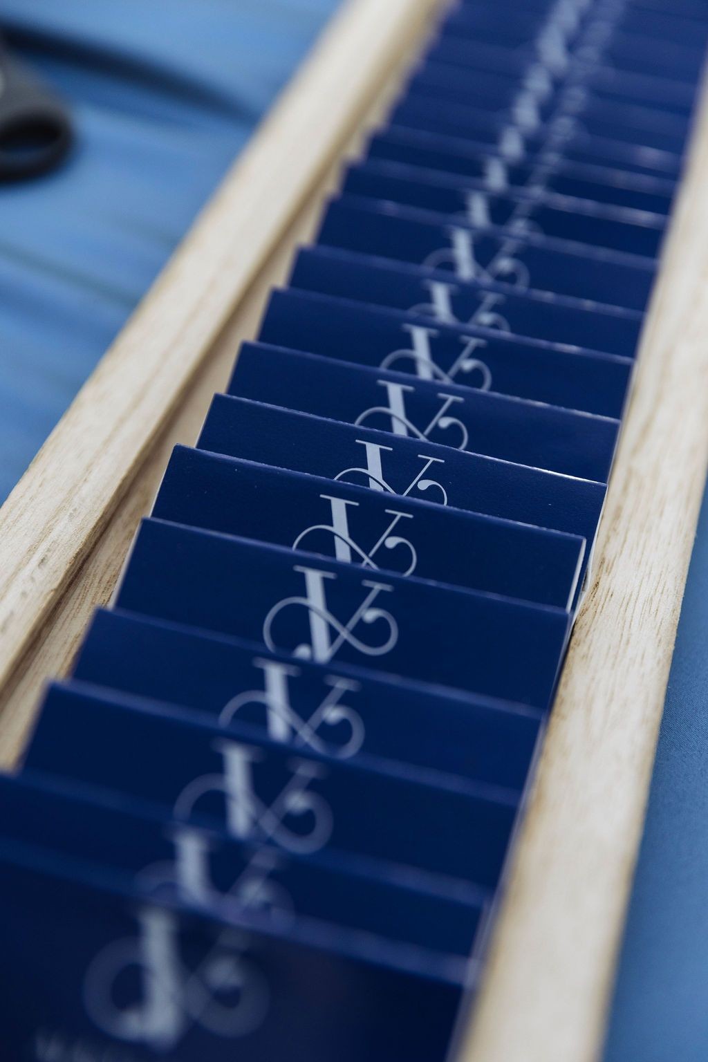 Blue dominoes lined up on a wooden tray, arranged in a row with white symbols on each tile