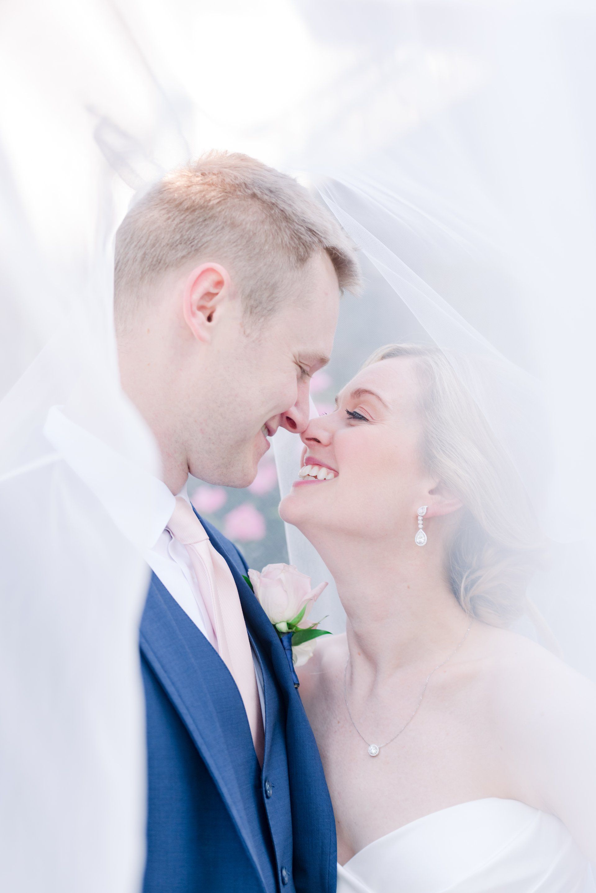 Bride and groom touching foreheads in a bright, soft-focus wedding portrait