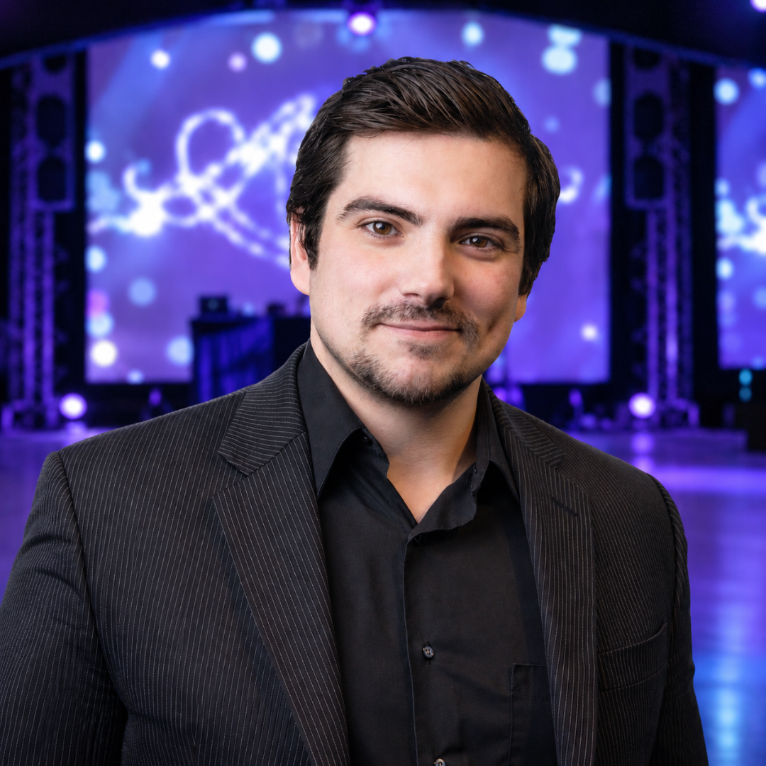 Smiling man in a dark suit at a purple-lit event