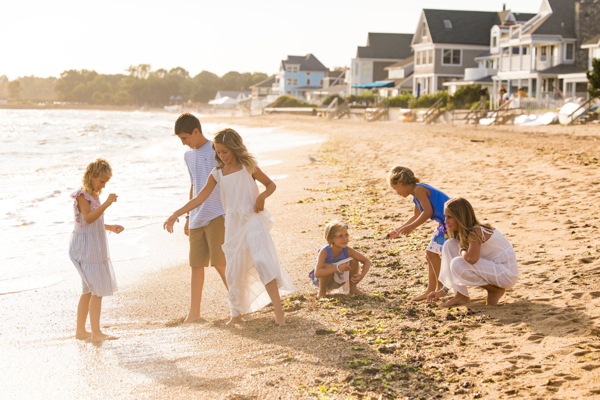 Family playing on a sandy beach at sunset near coastal houses