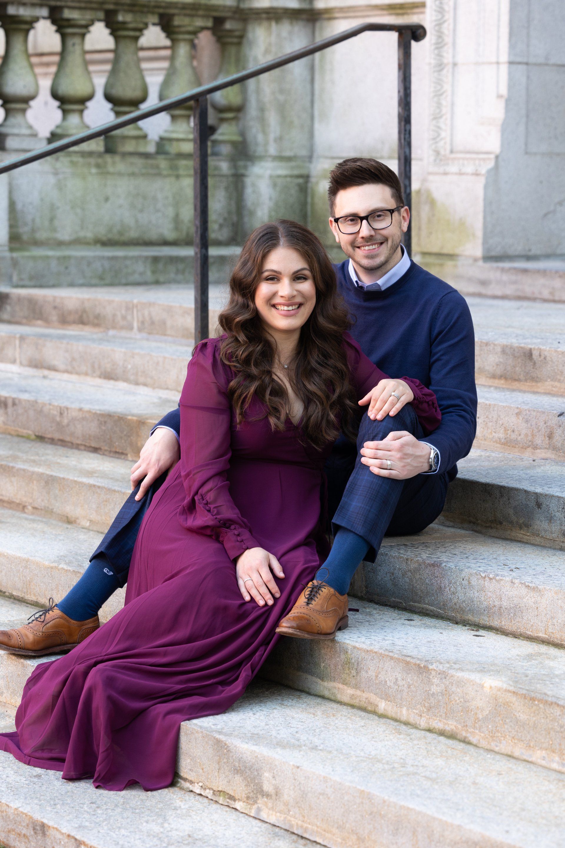 Couple sitting on stone steps, smiling and posed together outdoors.