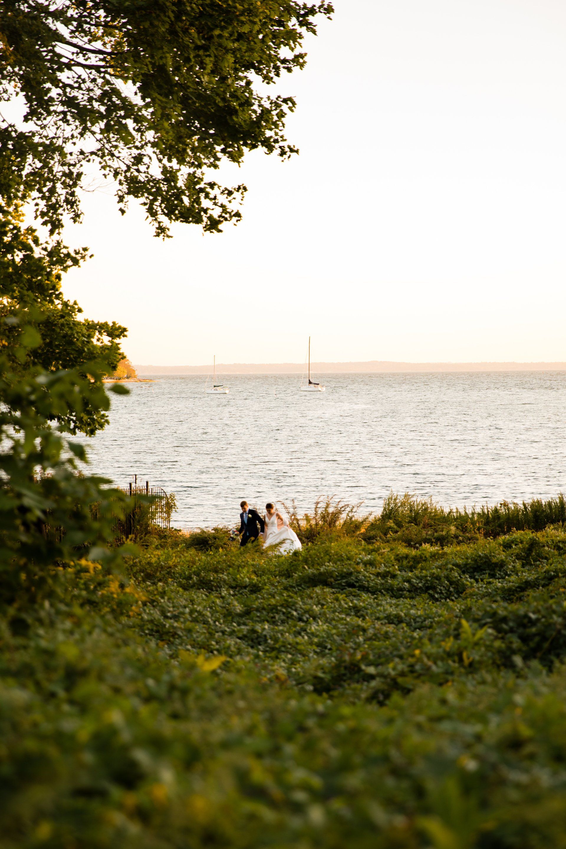 People sitting on a grassy shore overlooking a calm lake at sunset