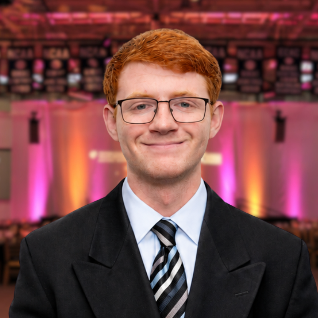 Smiling man in a dark suit at a purple-lit event