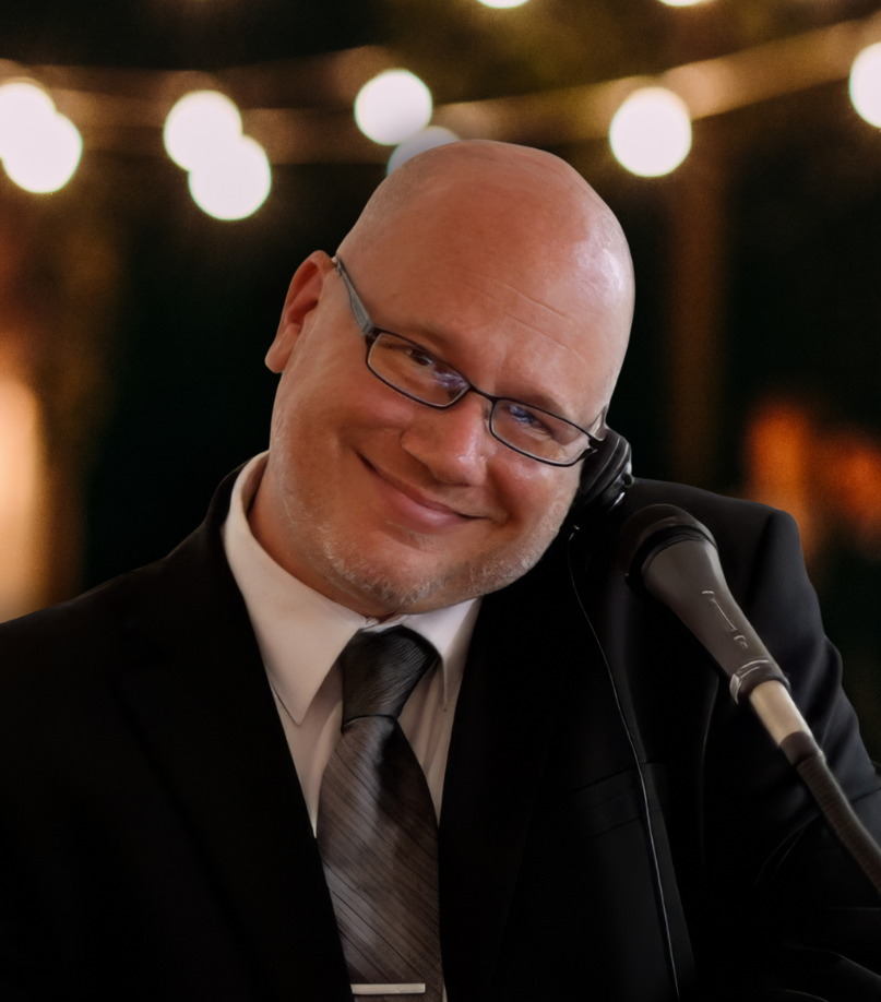 Smiling man in a suit holding a phone near a microphone at a podium