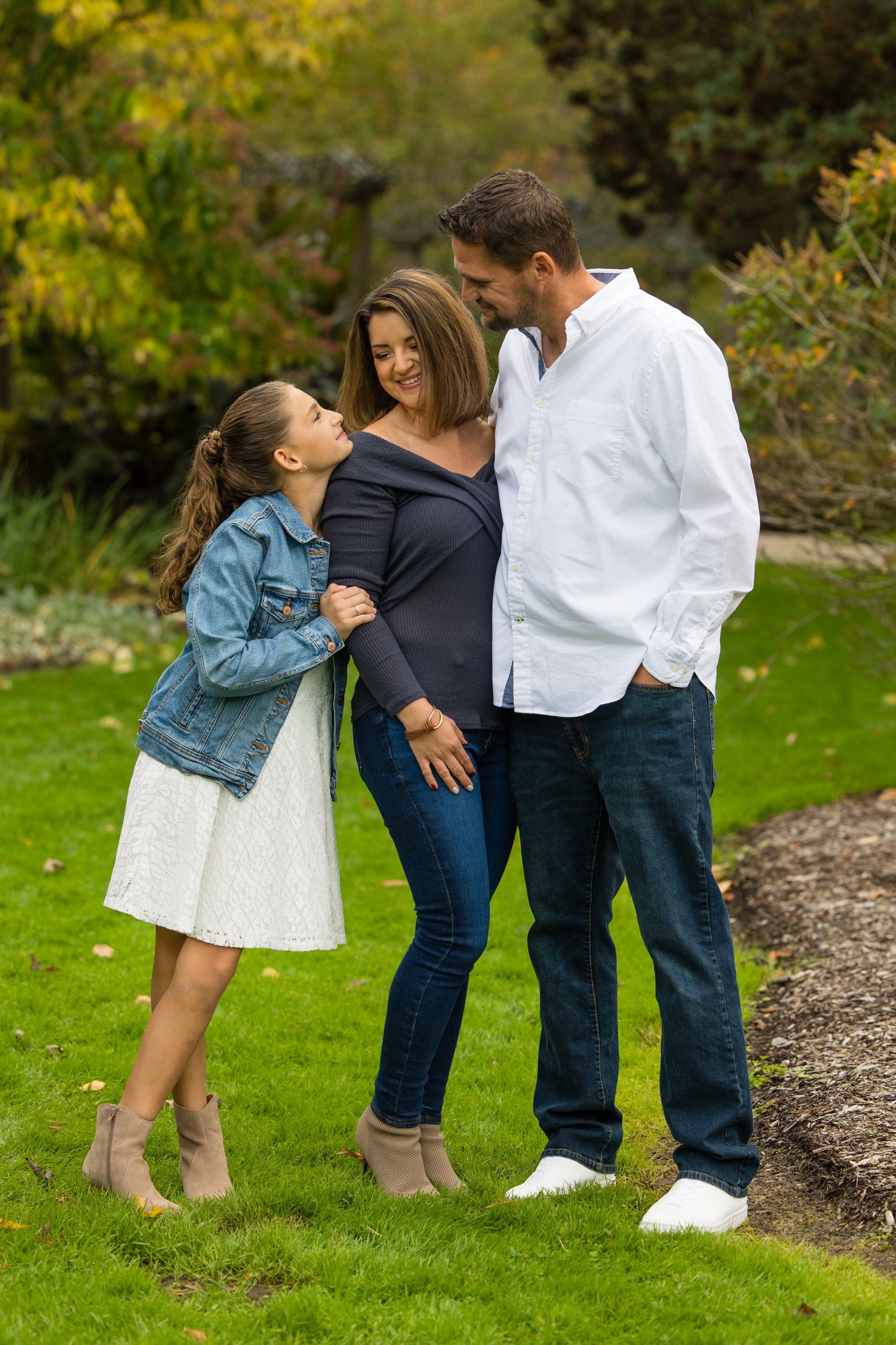 Family standing together outdoors on a grassy path, smiling and chatting in casual clothes