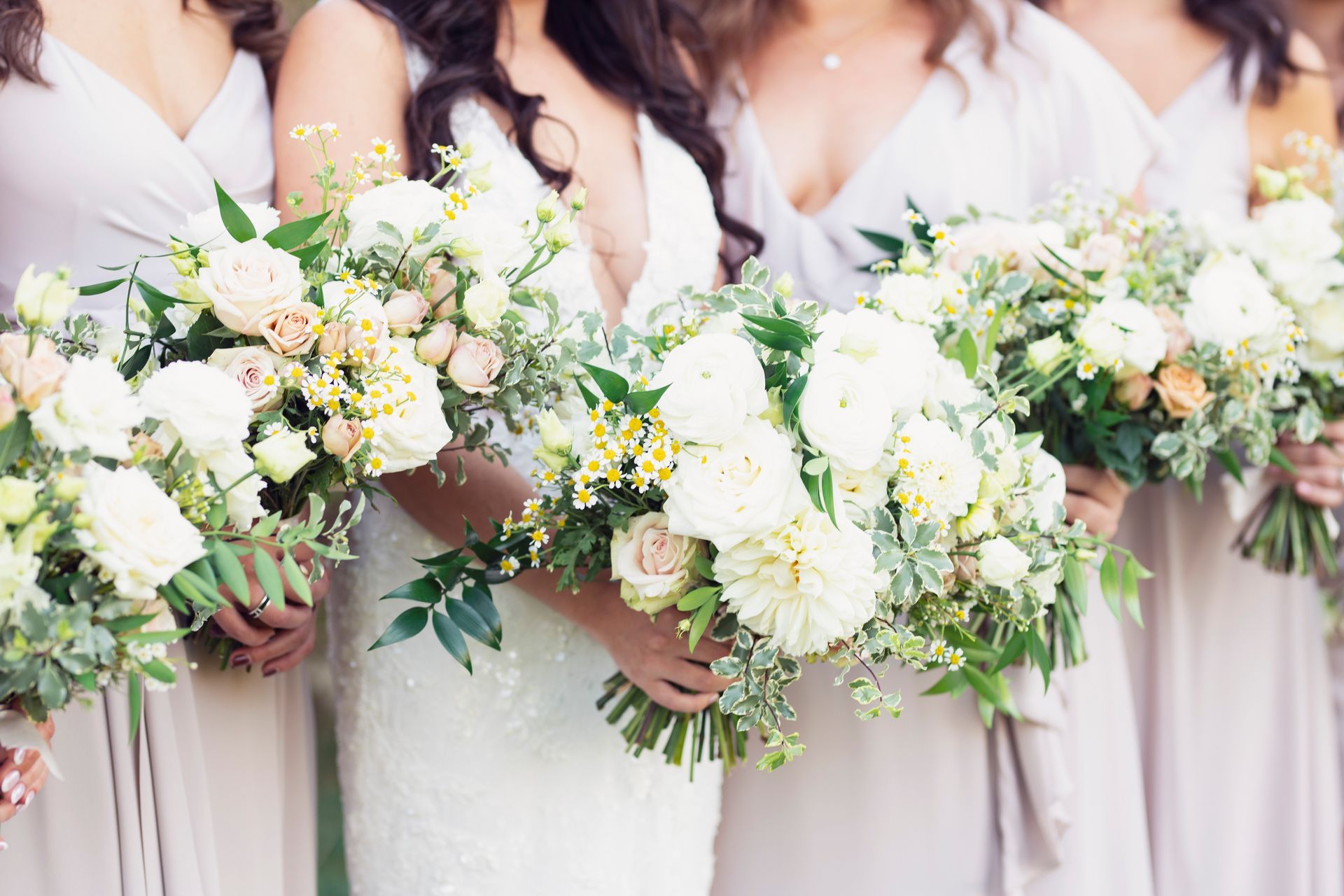 Bridesmaids holding white and pastel bouquets in soft blush dresses