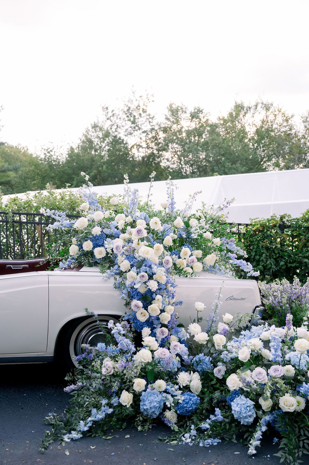 White car beside a cascading blue-and-white floral installation outdoors at an event