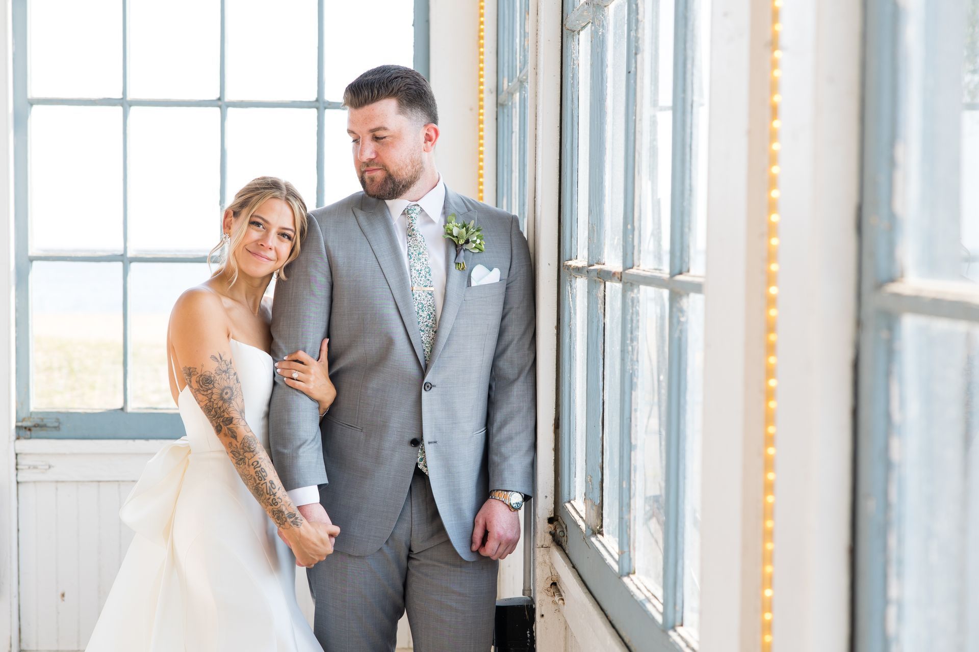 Bride and groom posing by bright windows in a sunlit room
