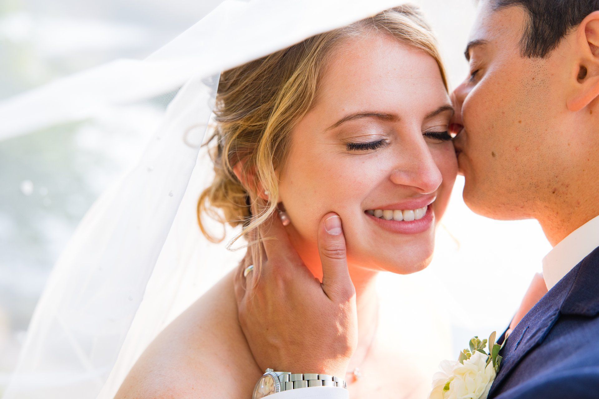 Bride smiling as a groom kisses her cheek during their wedding ceremony