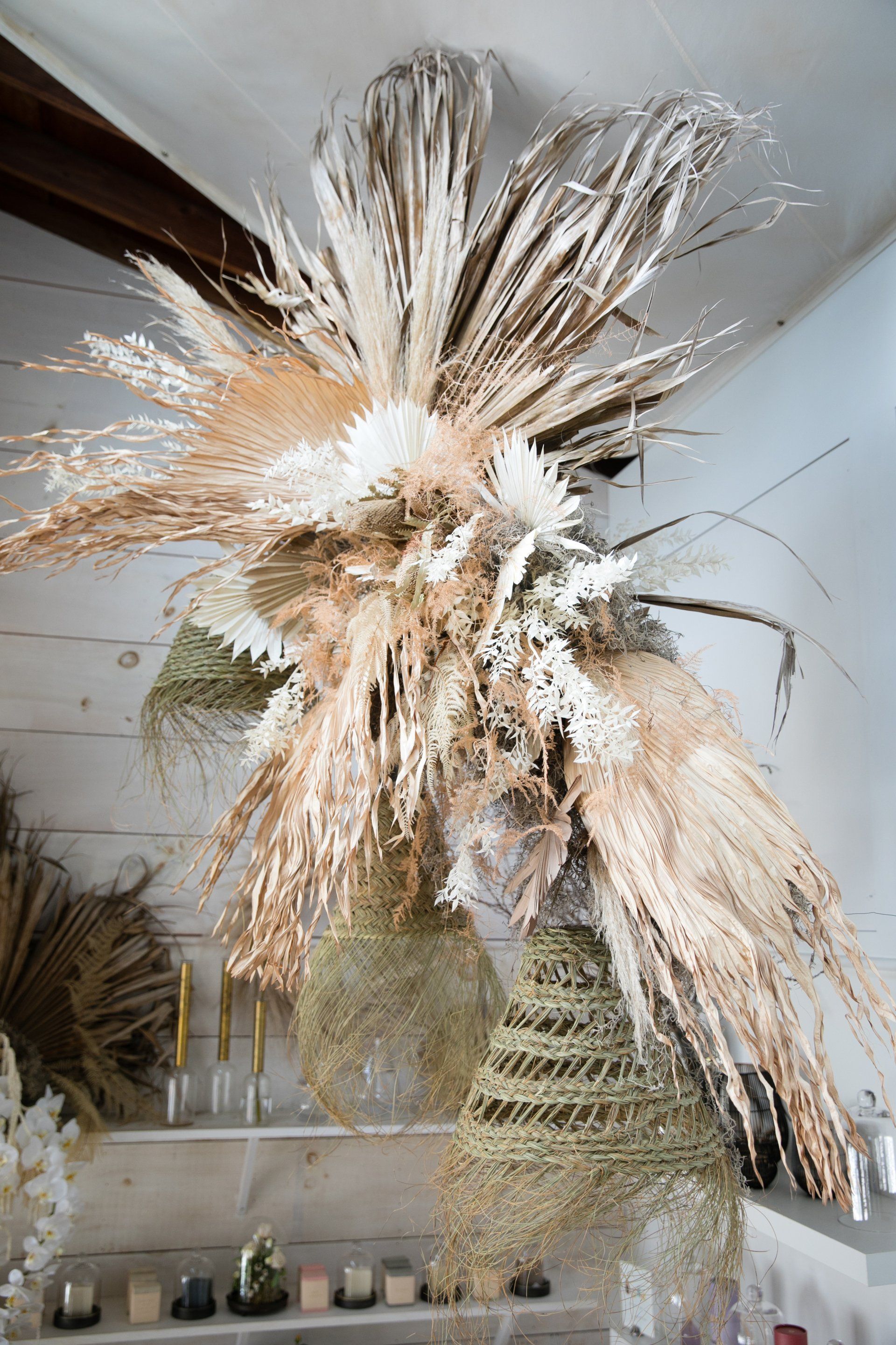 A tall dried pampas grass arrangement in a bright room with shelves and decor