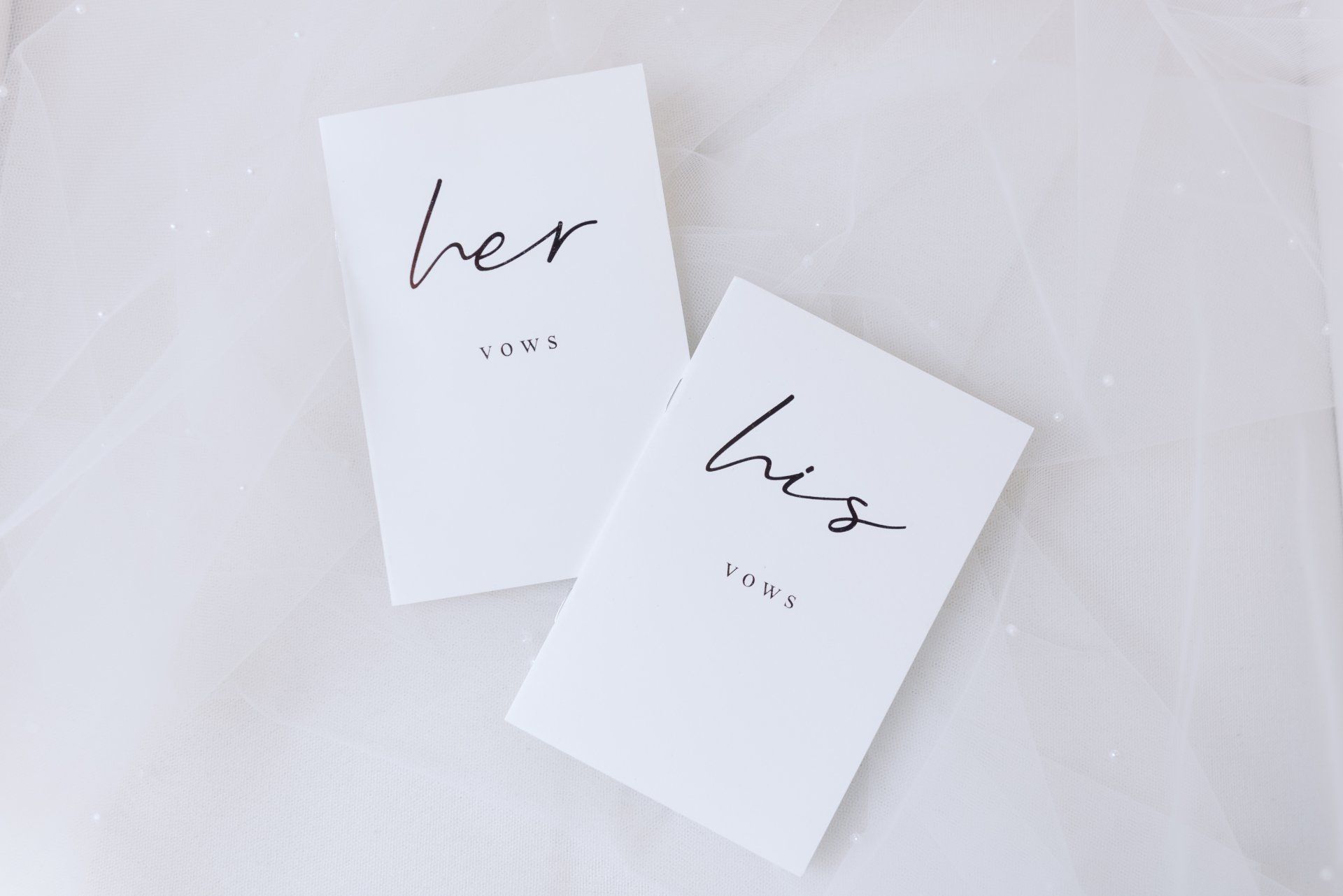 Two white cards on a soft white fabric background, labeled “her” and “him.”