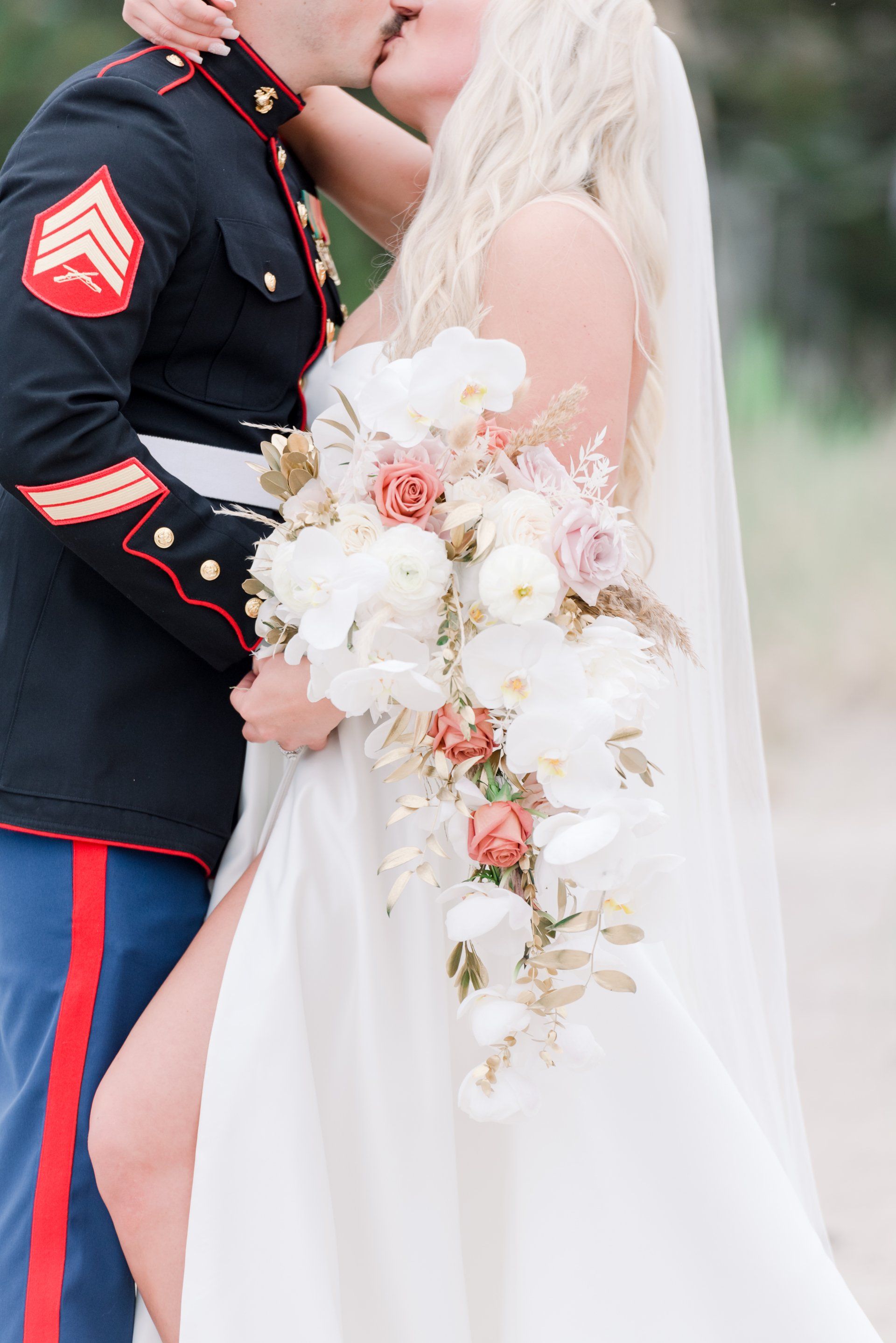Bride and groom kissing, bride holding cascading white and blush bouquet.