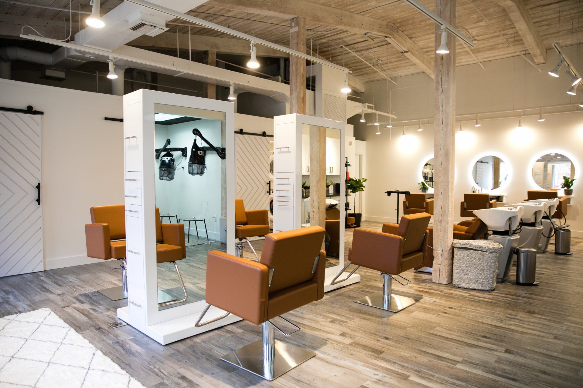 Modern salon with orange chairs, mirrors, and styling stations in a bright industrial interior