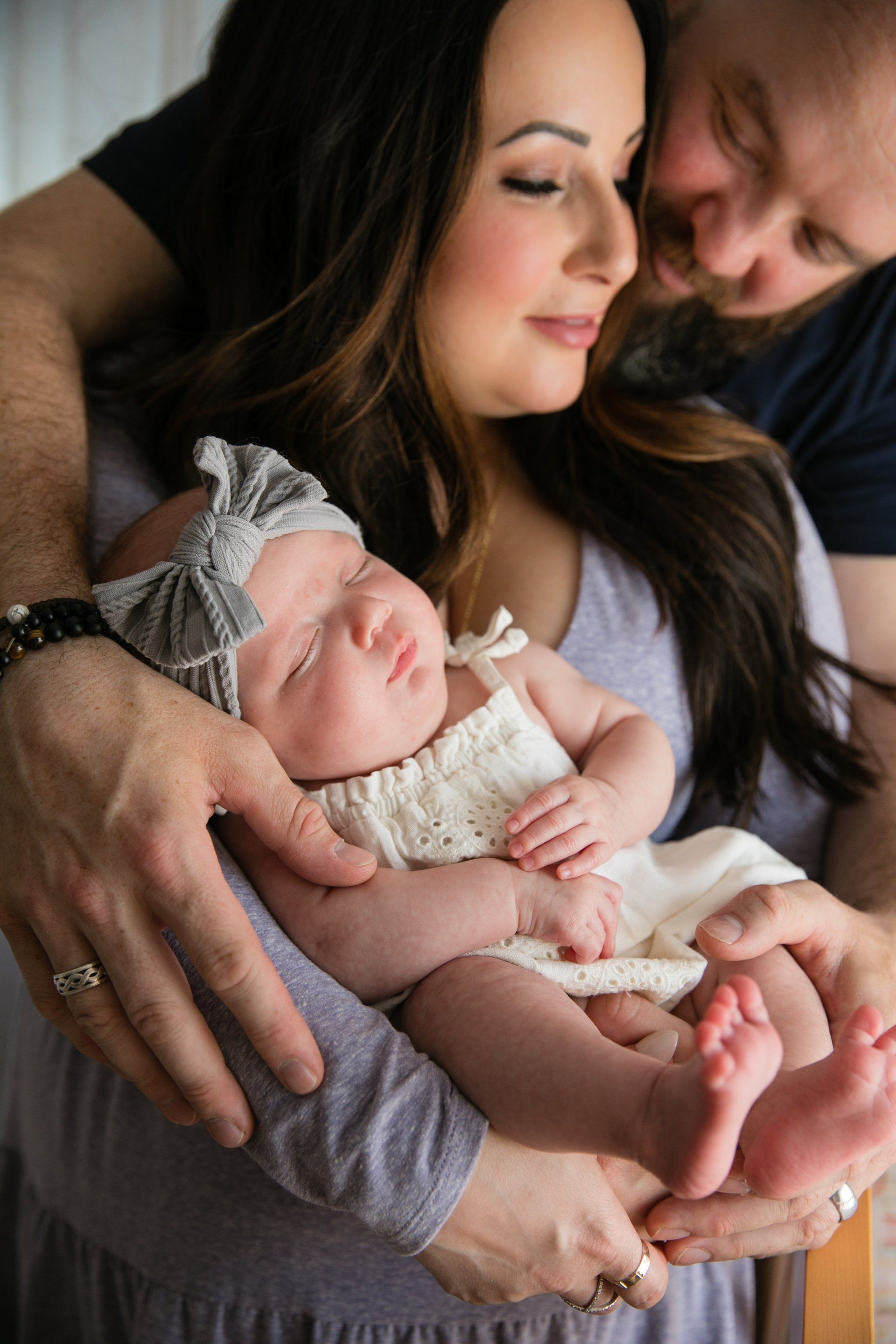 Parents holding a sleeping newborn in a cozy indoor family portrait