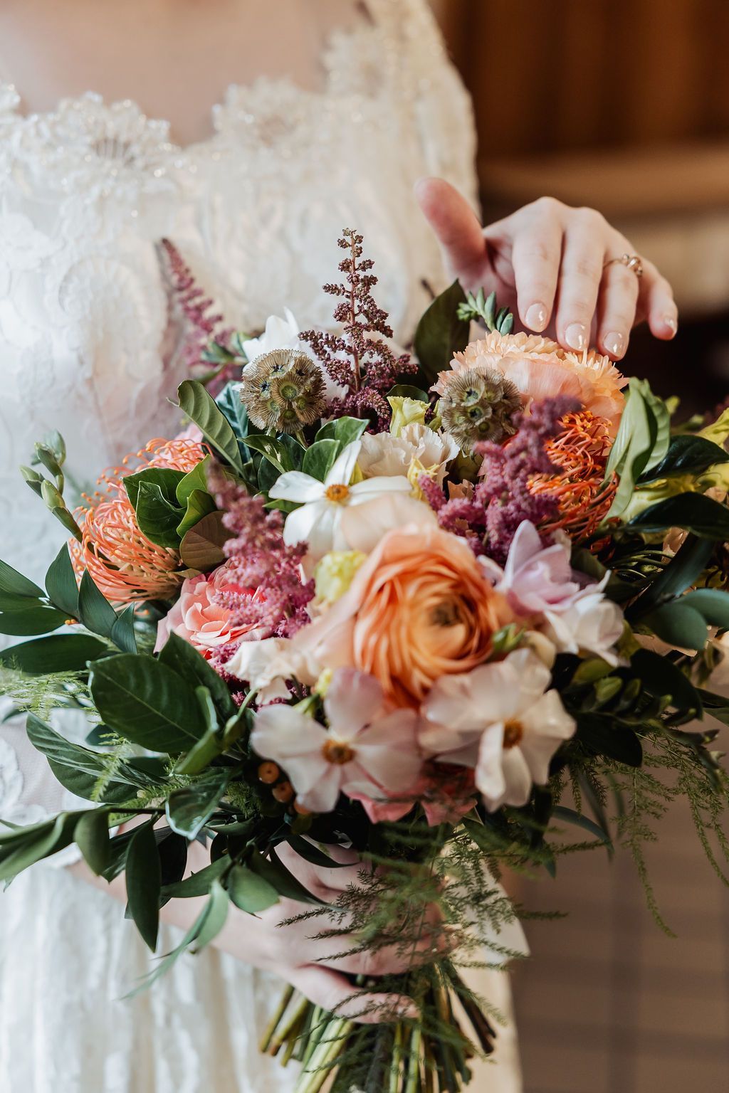 Bride holding a lush pastel bouquet of roses, orchids, and greenery
