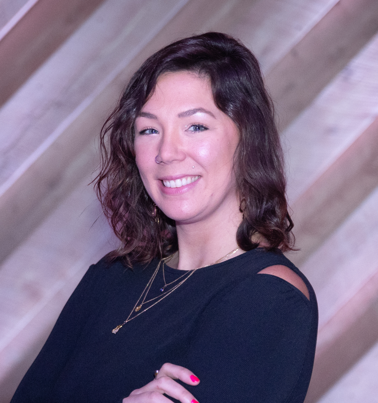 Smiling woman in a black top posing against a wooden backdrop