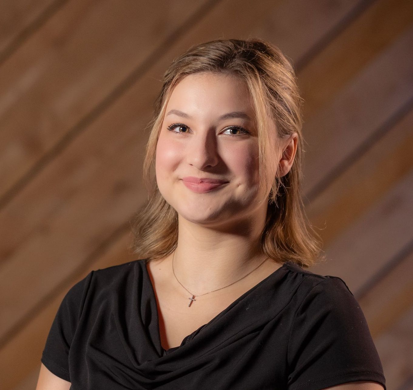 Smiling woman in a black top against a wooden diagonal background
