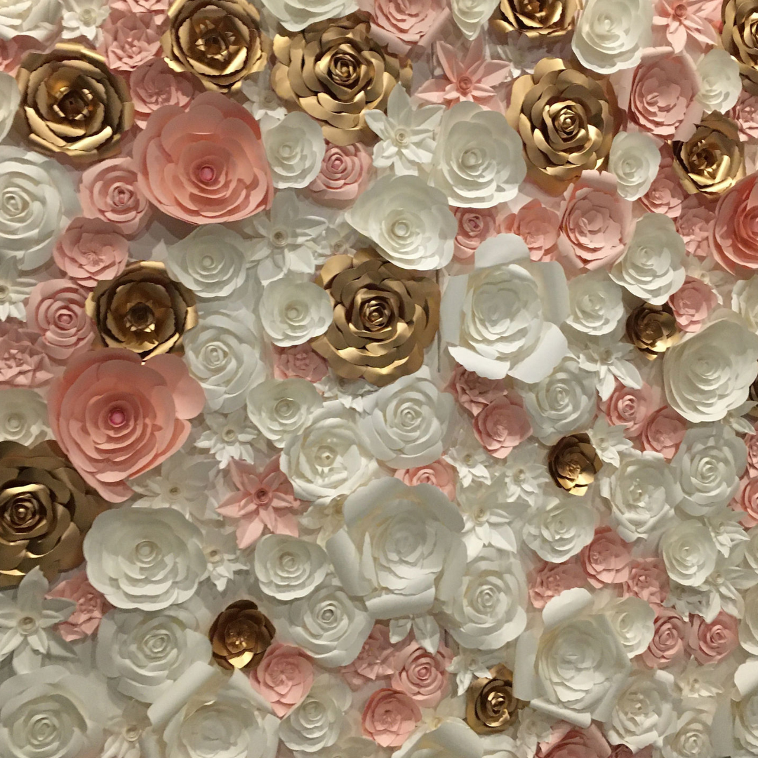 Couple posing in front of a floral rose backdrop at an event, smiling and embracing.