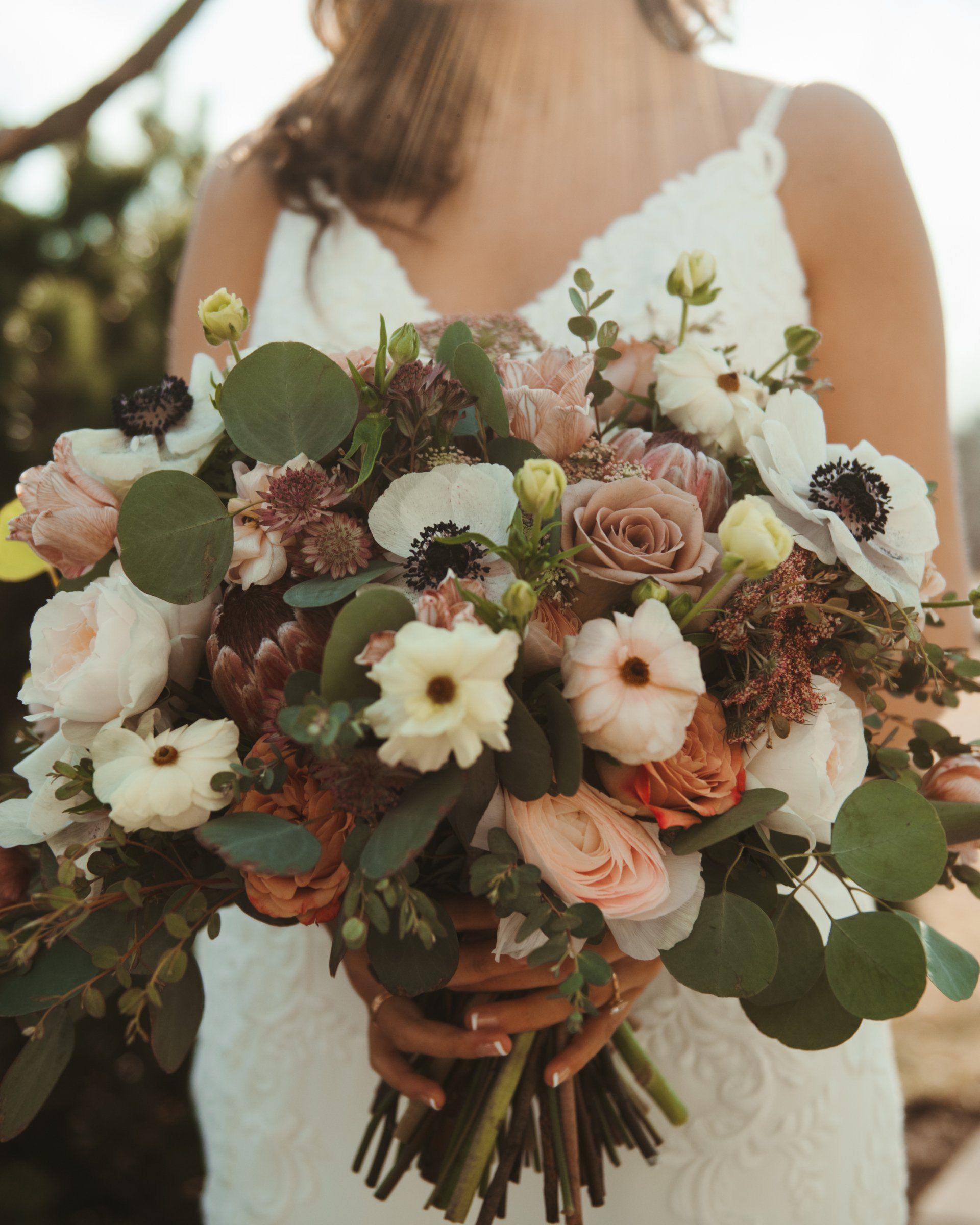 Bride holding a lush pastel bouquet of roses, daisies, and greenery
