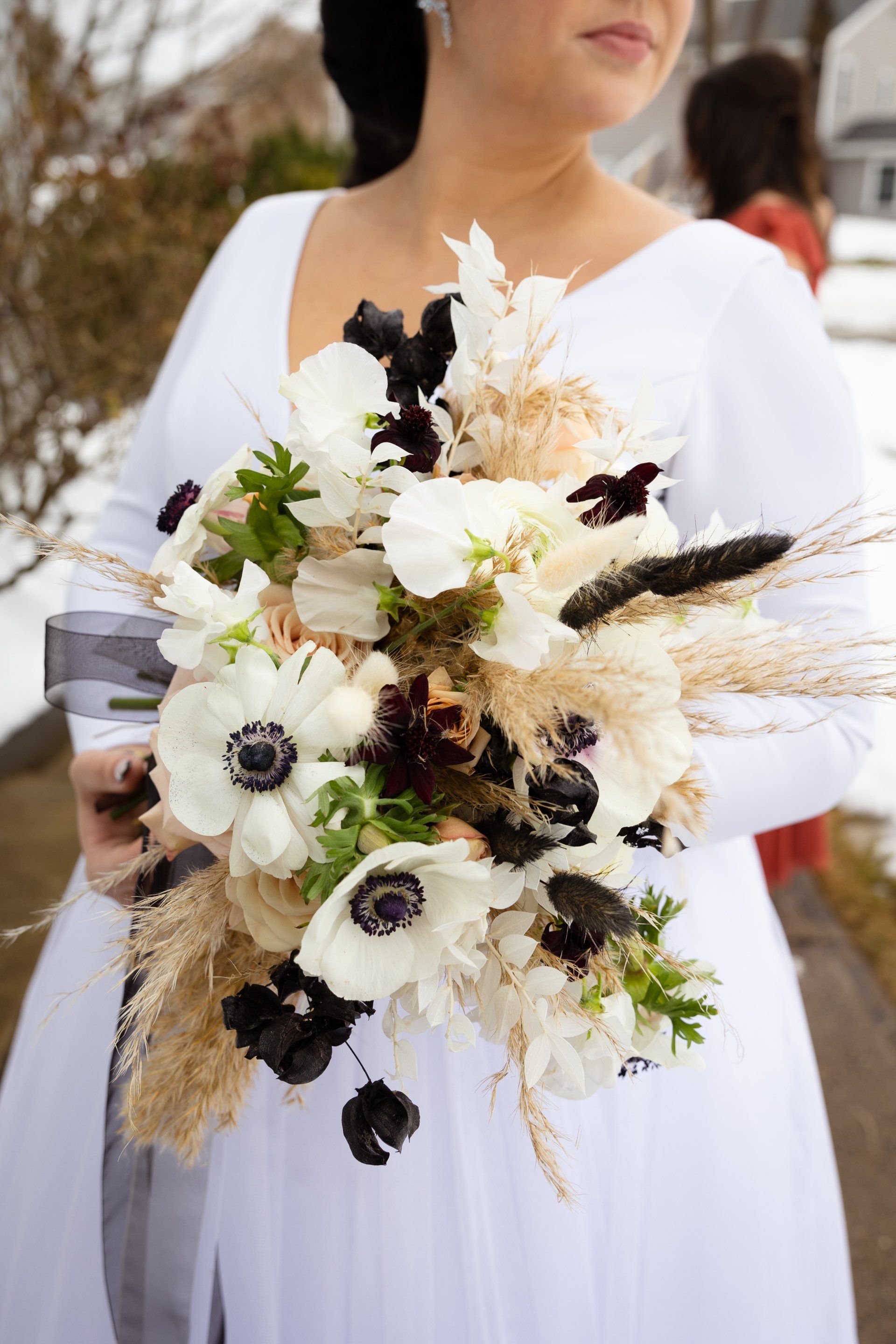 Woman holding a white and black floral bouquet in a white dress