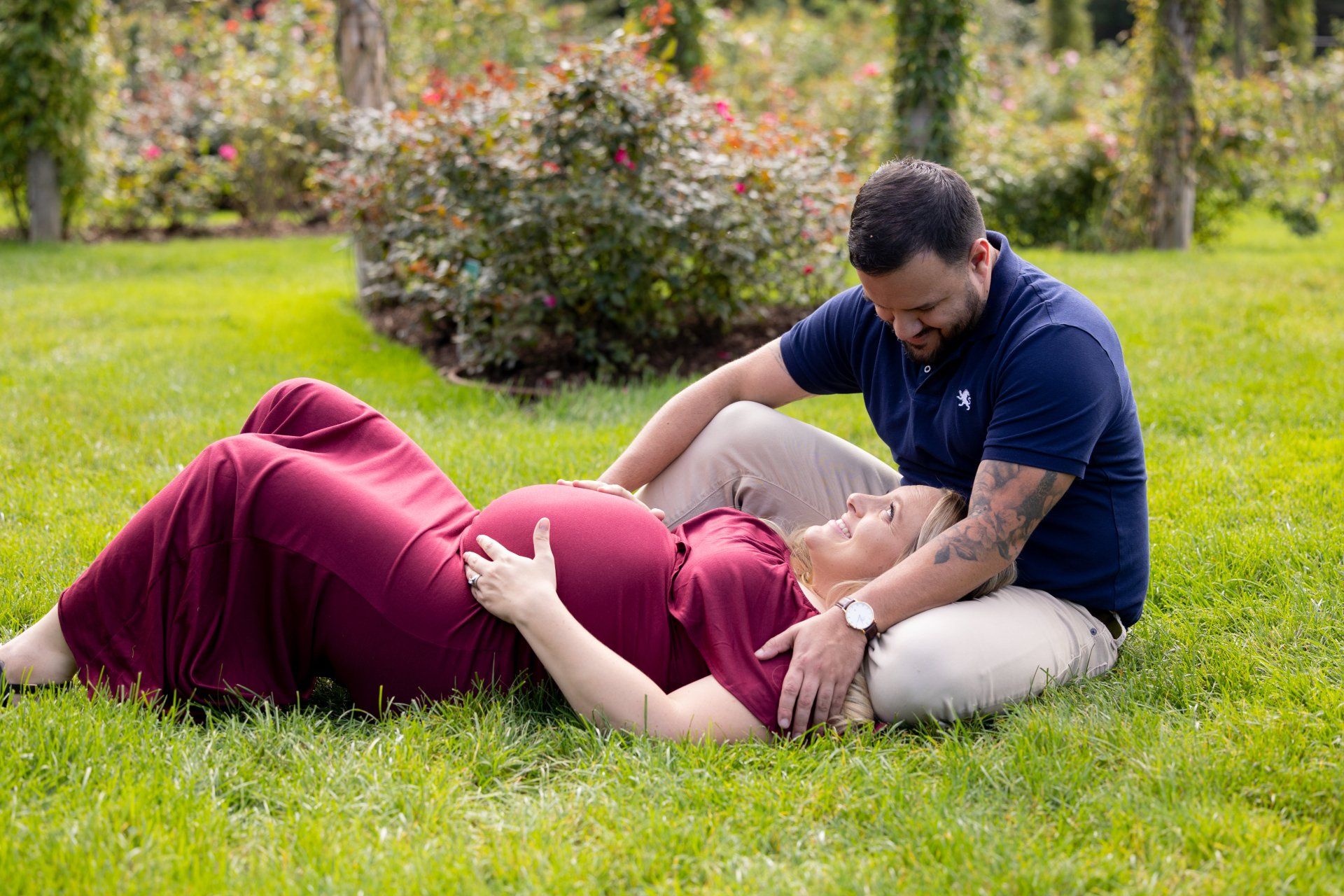 Person receiving a seated massage on grass in a park, with another person leaning over them.