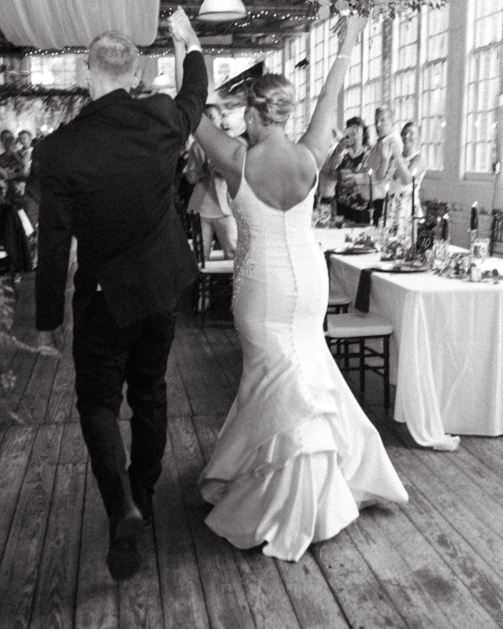 Bride in a white dress dances with a man at a rustic wedding reception.