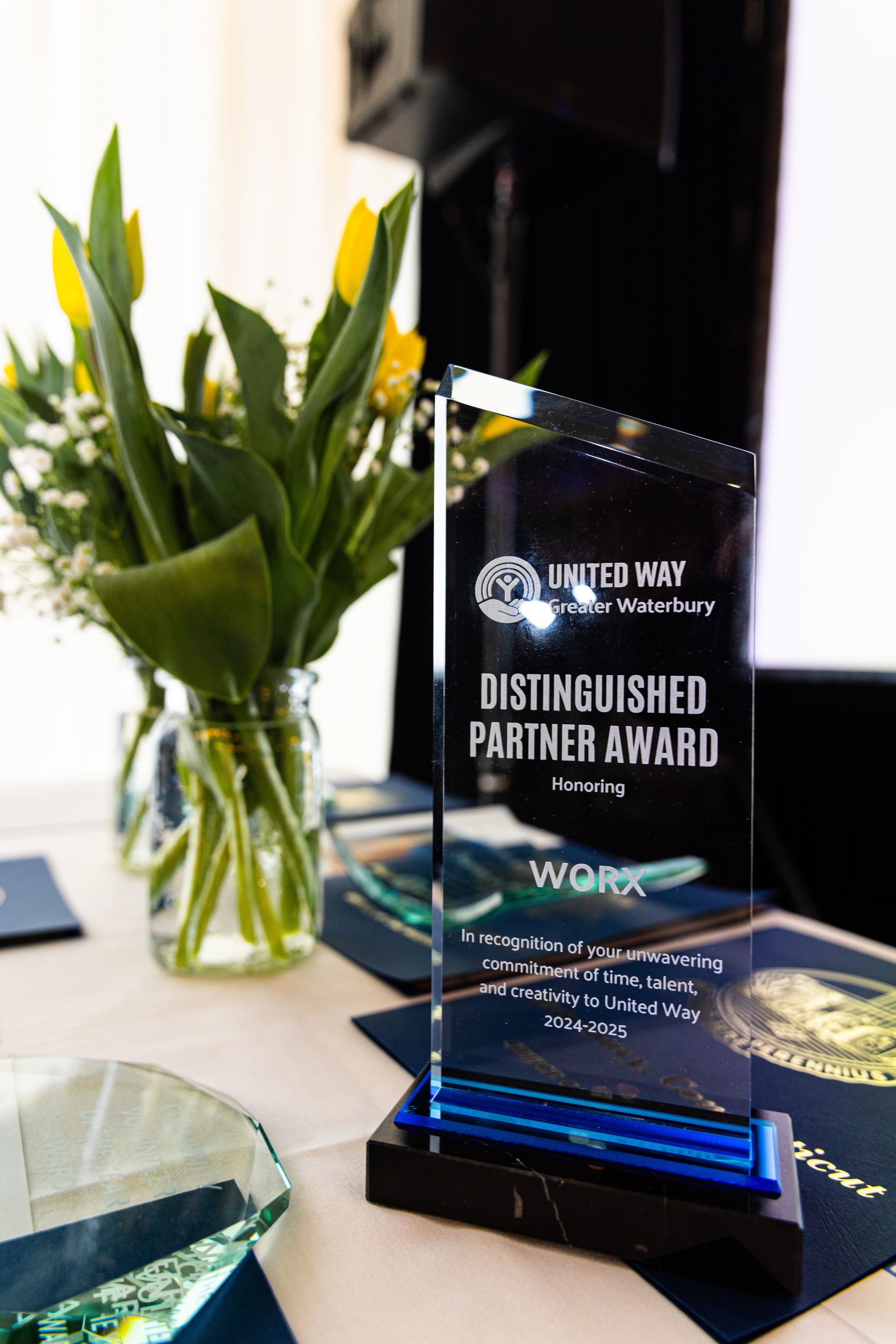Distinguished Partner Award plaque beside a vase of white flowers on a table