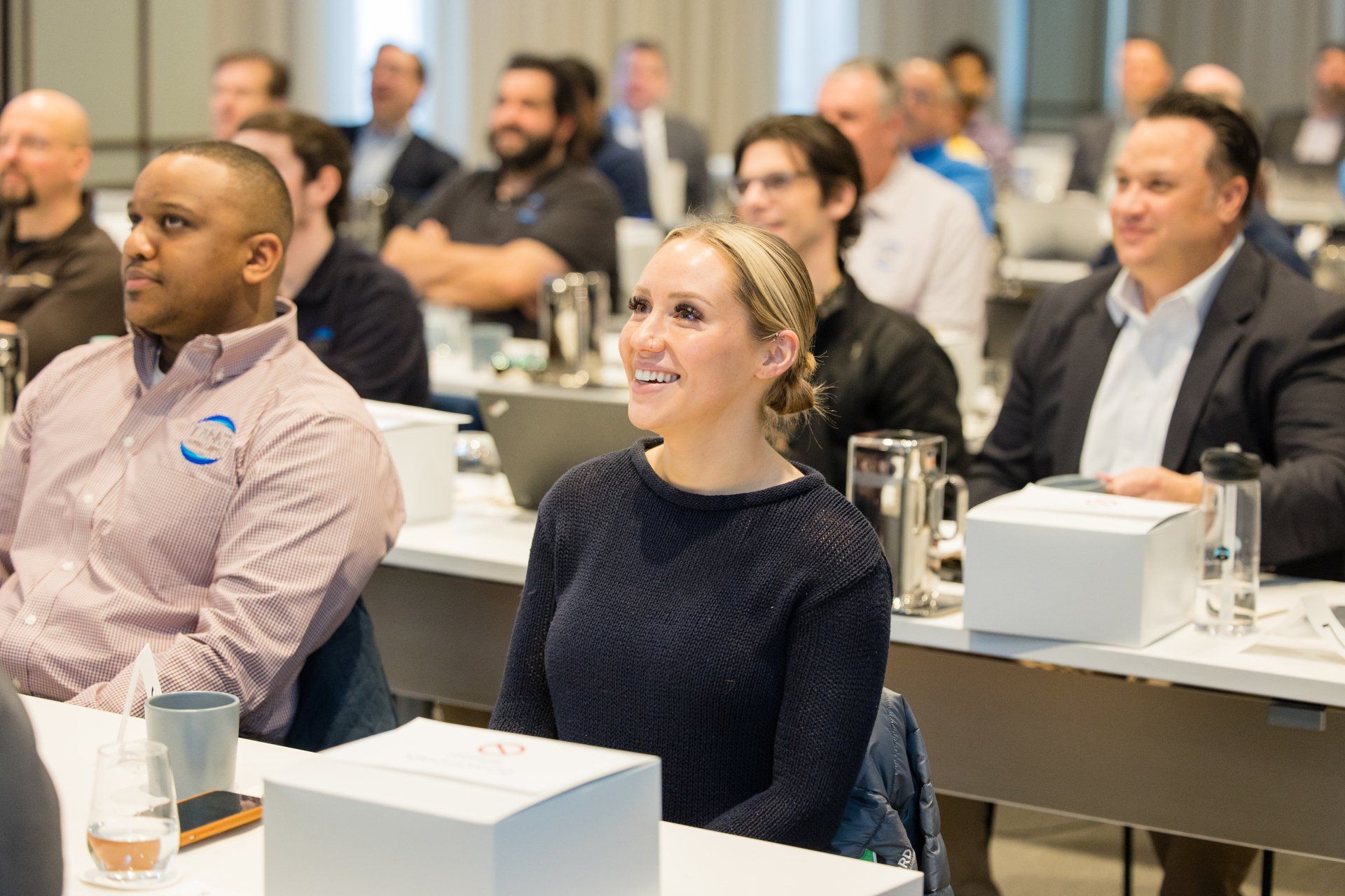 Audience seated in a conference room, listening attentively at a presentation.