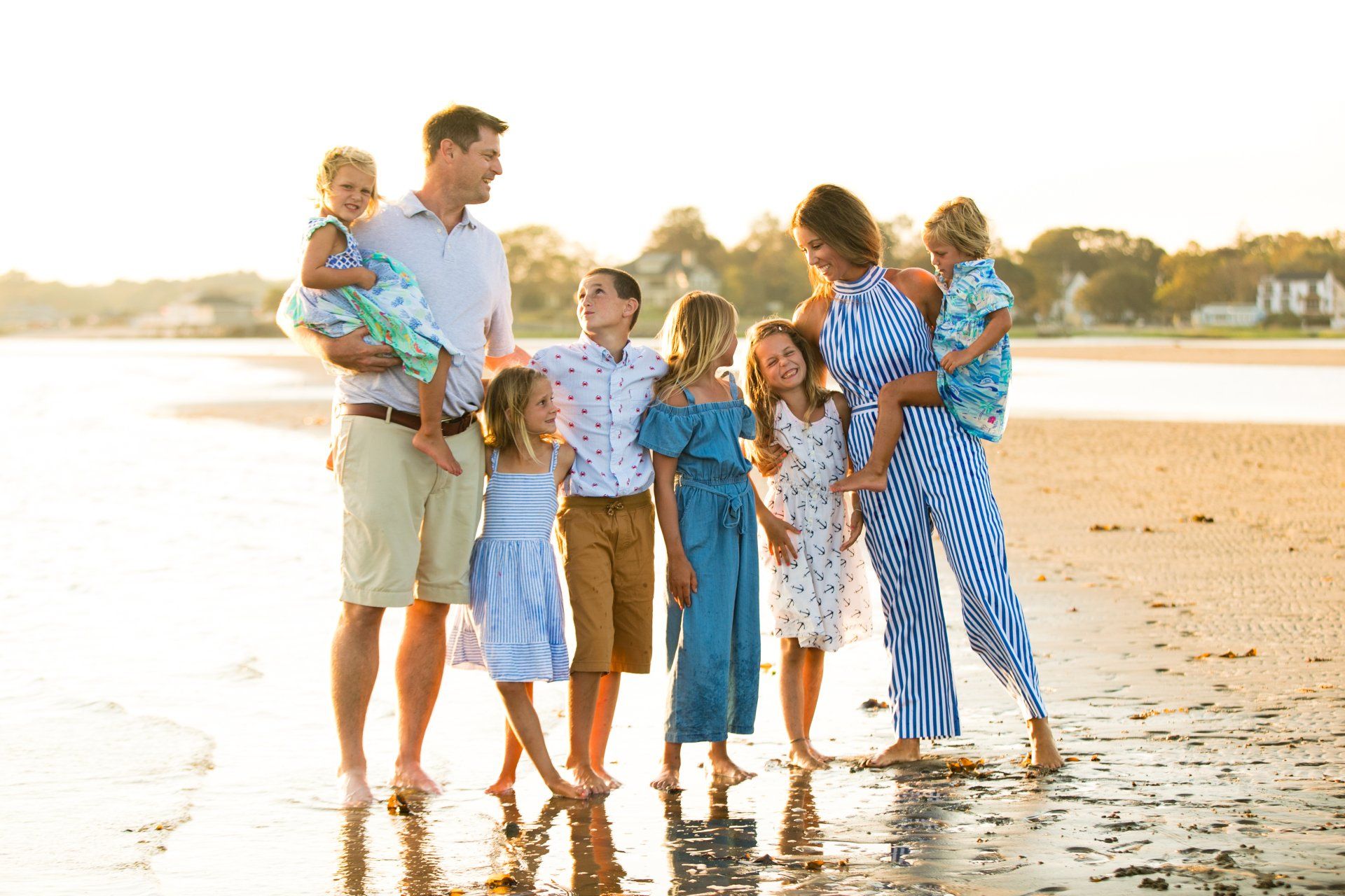 Family standing on a sunlit beach, smiling and posing at the shoreline