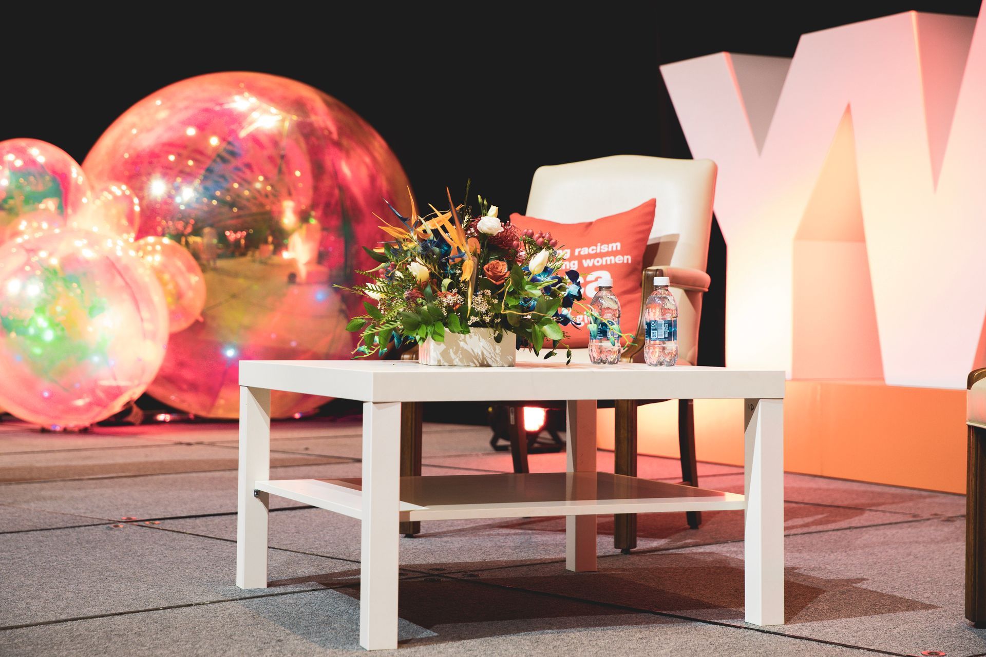 White coffee table with flowers and balloons in a colorful indoor event setup