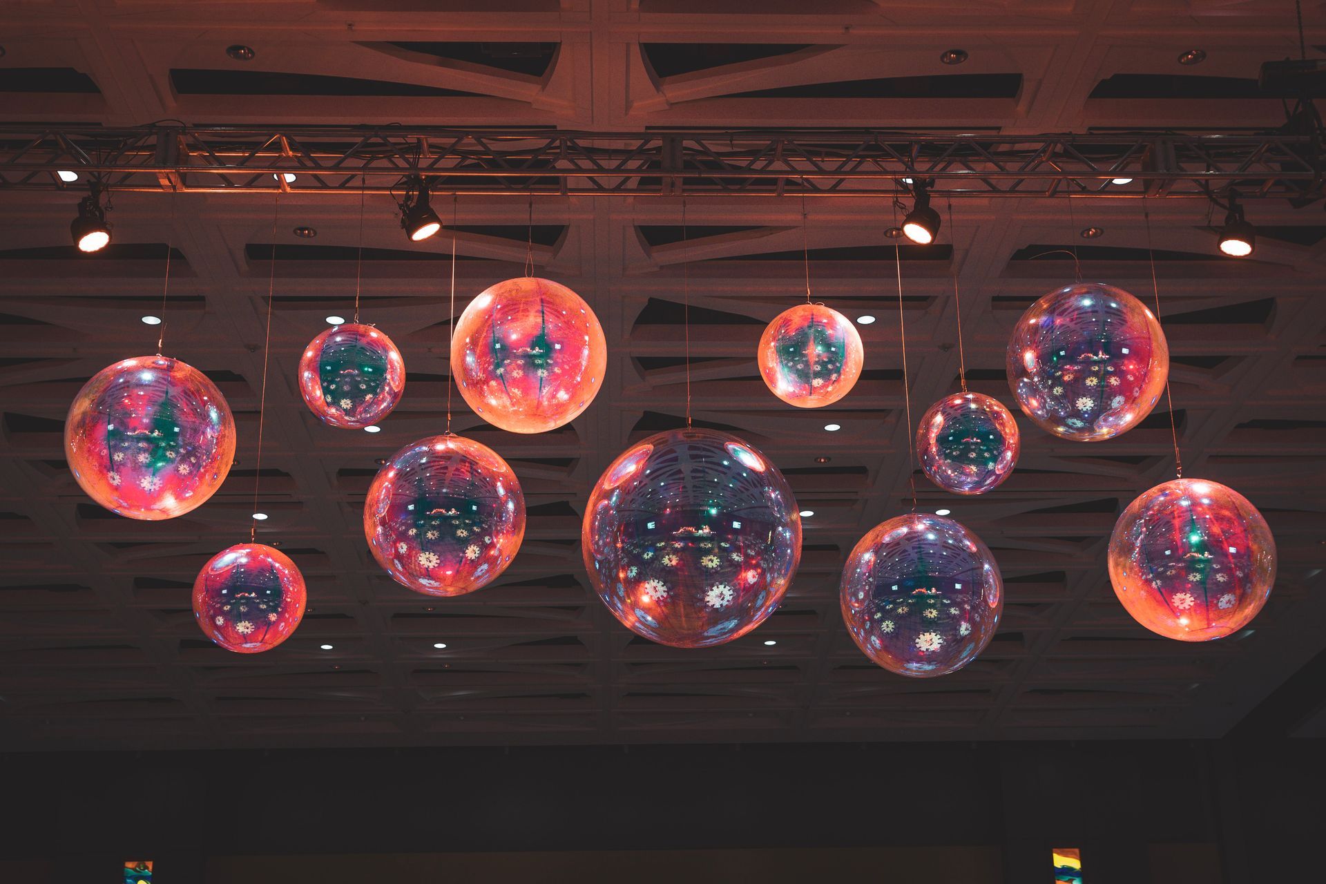 Colorful glowing hanging spheres in a dim indoor ceiling installation