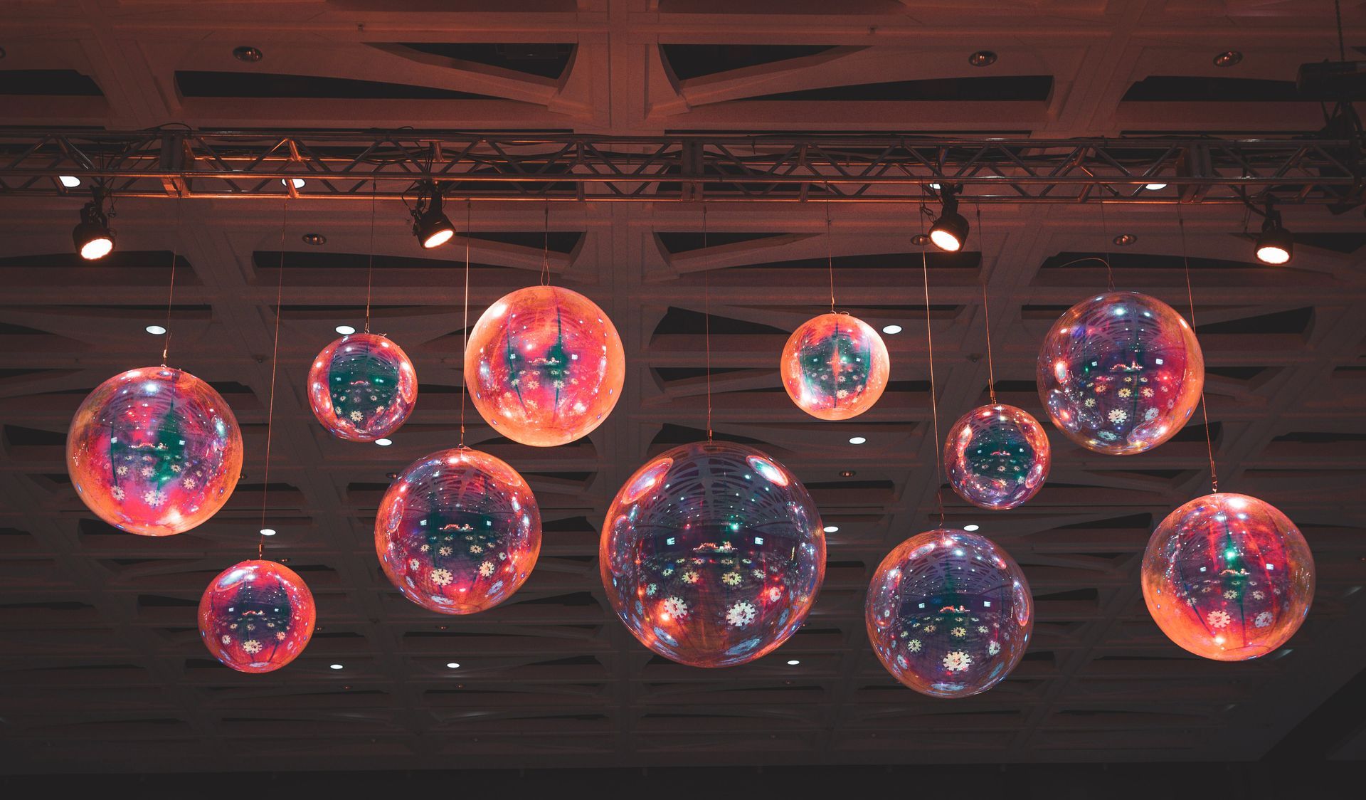 Colorful glowing orbs hang from a ceiling in a dim indoor space.