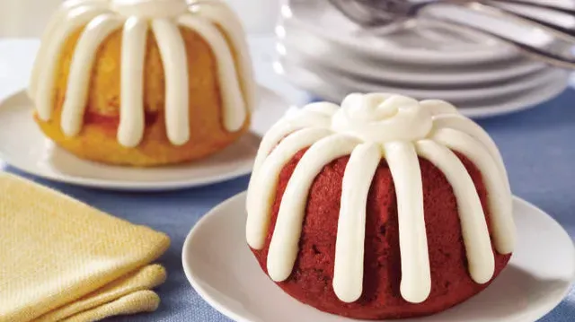 A woman is sitting at a desk using a laptop computer to have a video call with her colleagues.