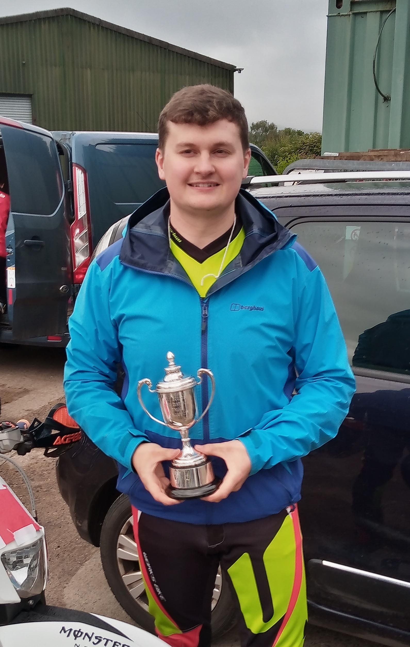 A man in a blue jacket is holding a trophy