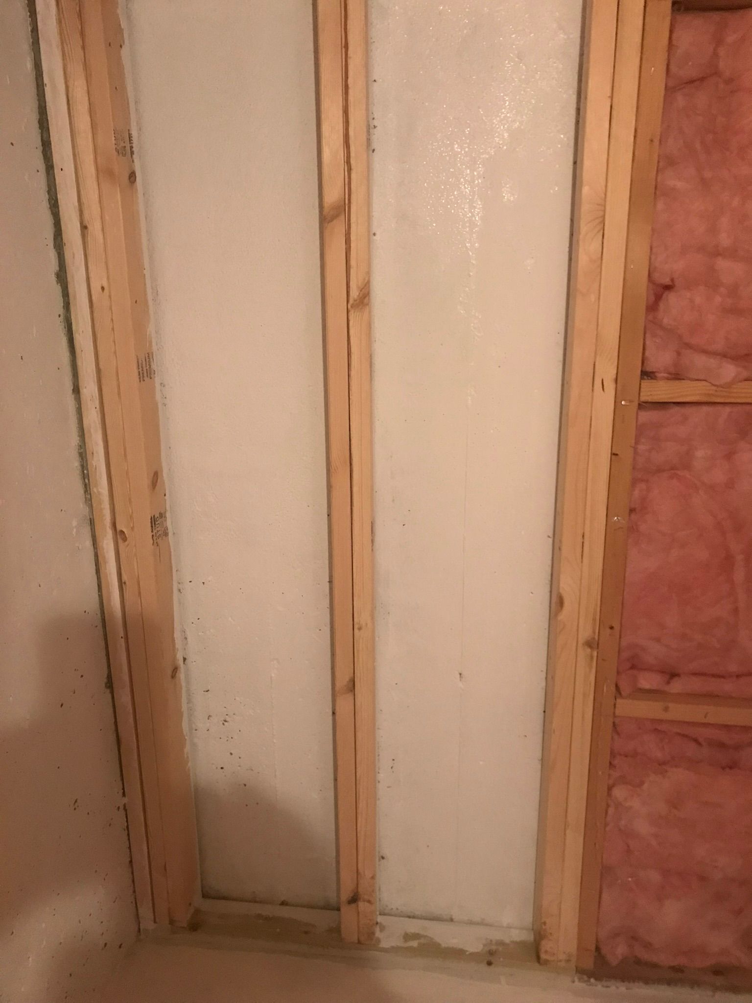 Partially finished wall framing with white foam board and pink insulation on the right
