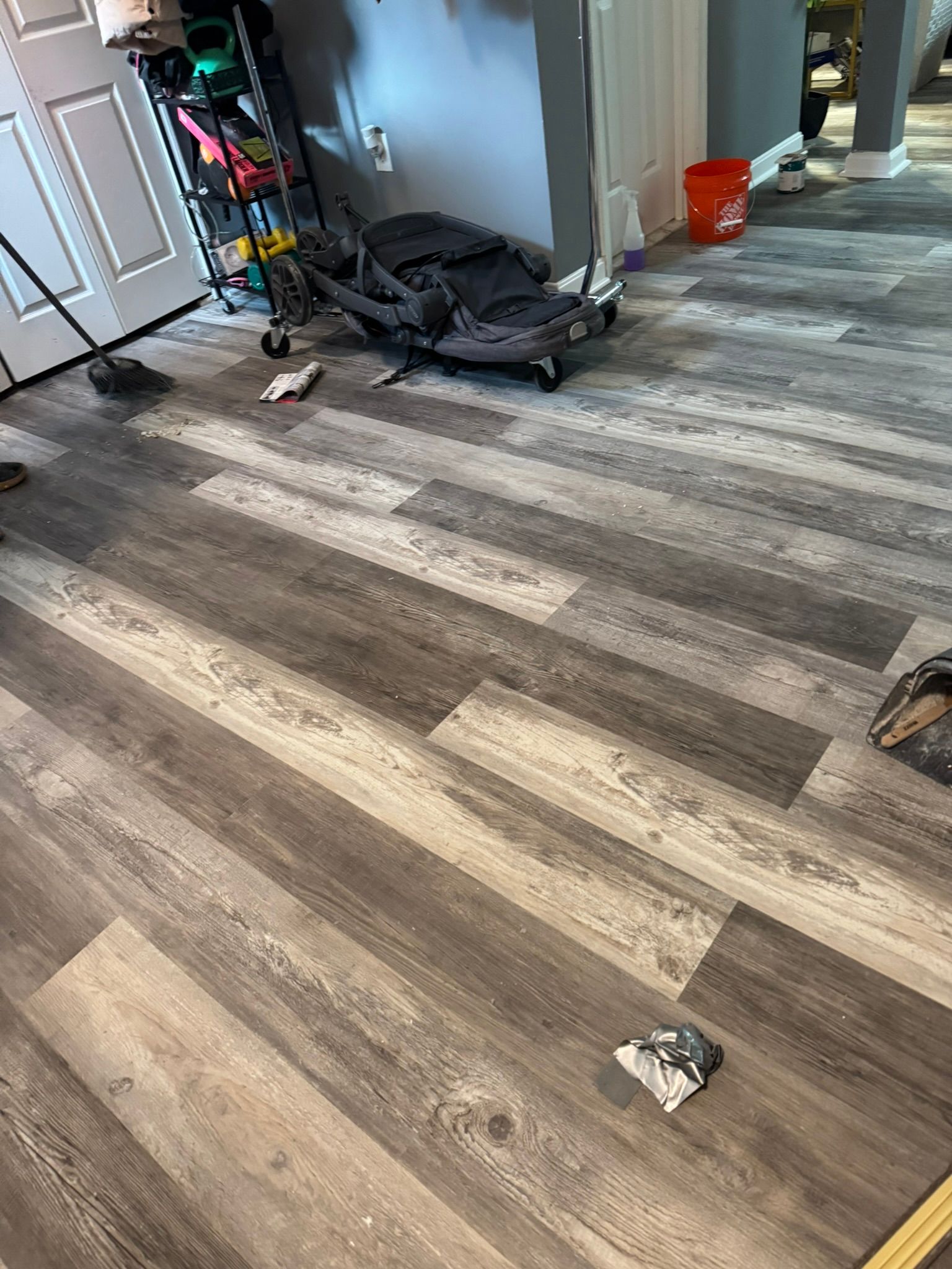 Living room with wood-look floor, a stroller, and small items scattered near the wall
