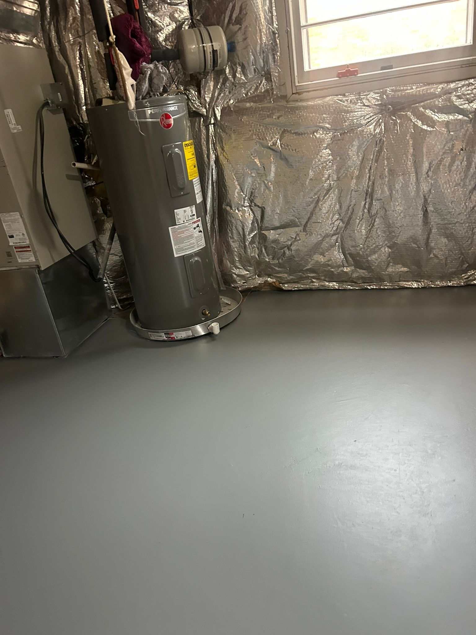 Basement utility room with a water heater, insulated walls, and a gray concrete floor.