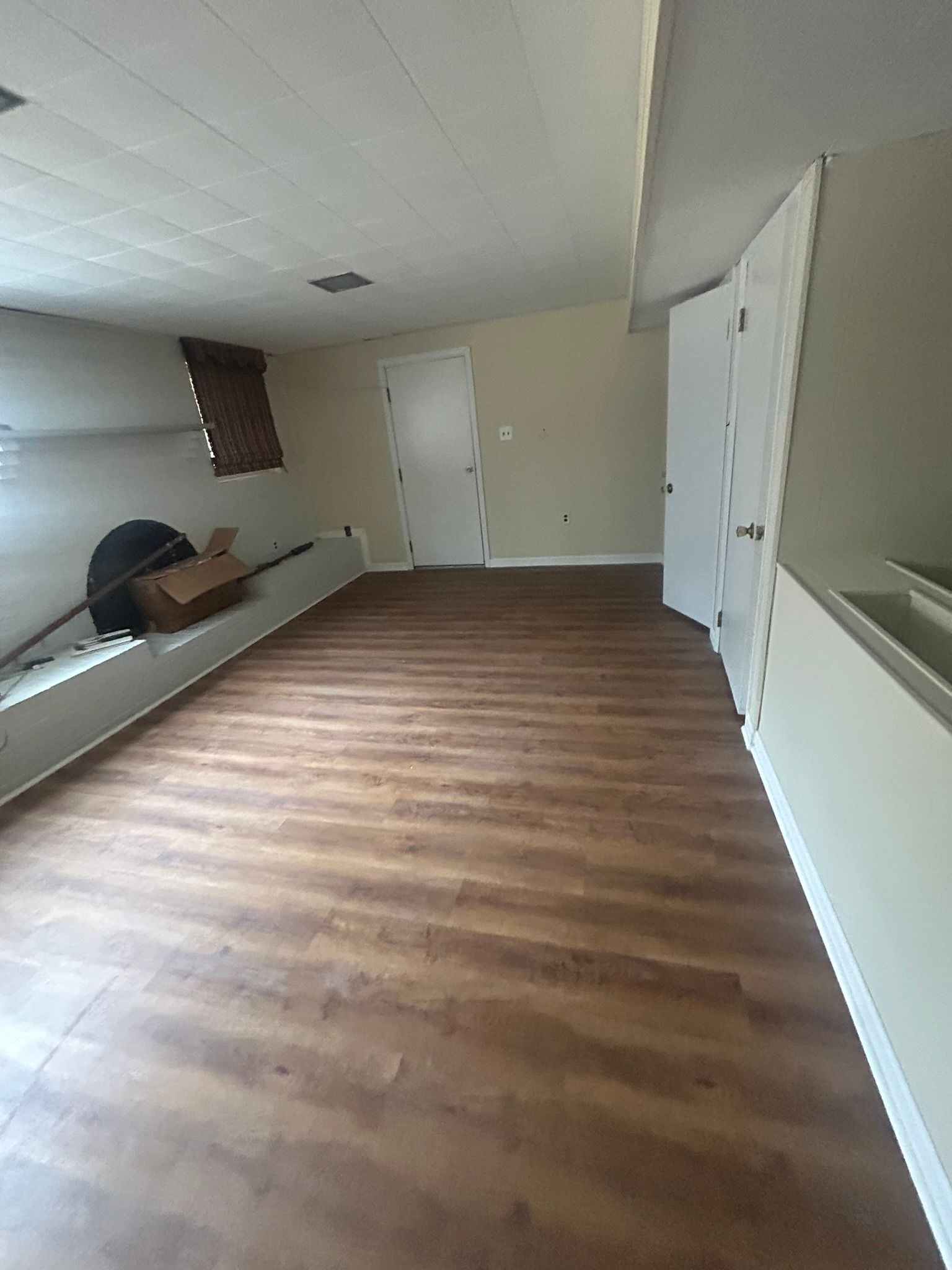 Empty room with wood flooring, white walls, and a closed door, viewed from a low angle.