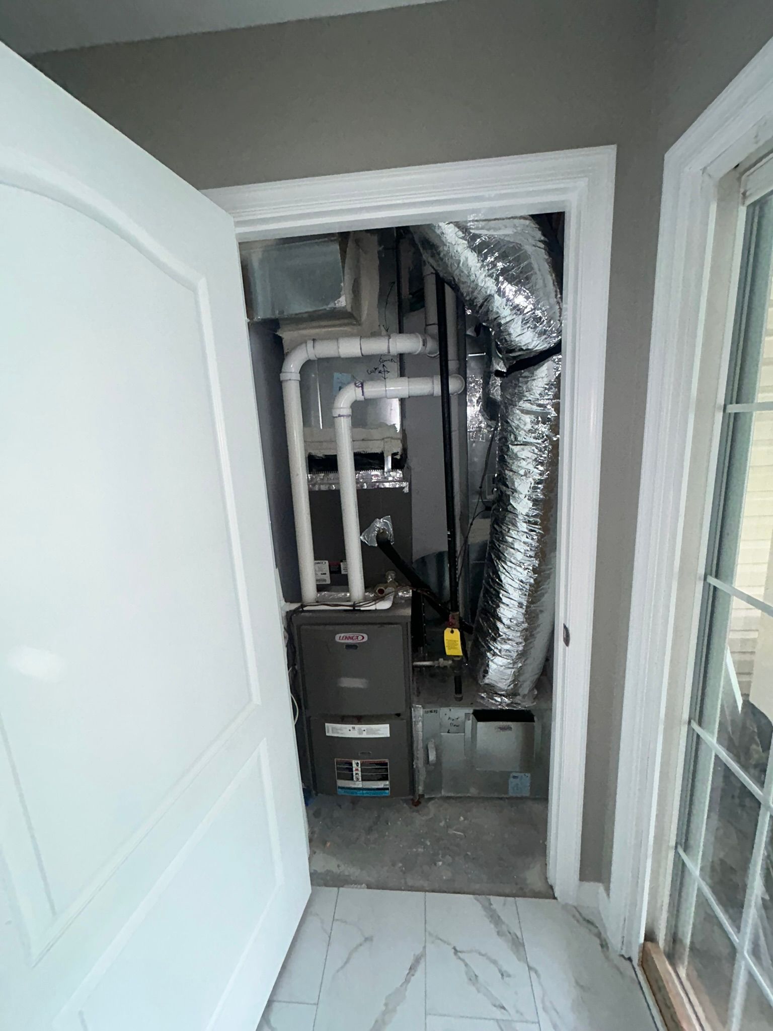 Open closet with HVAC furnace and ductwork inside a small hallway alcove