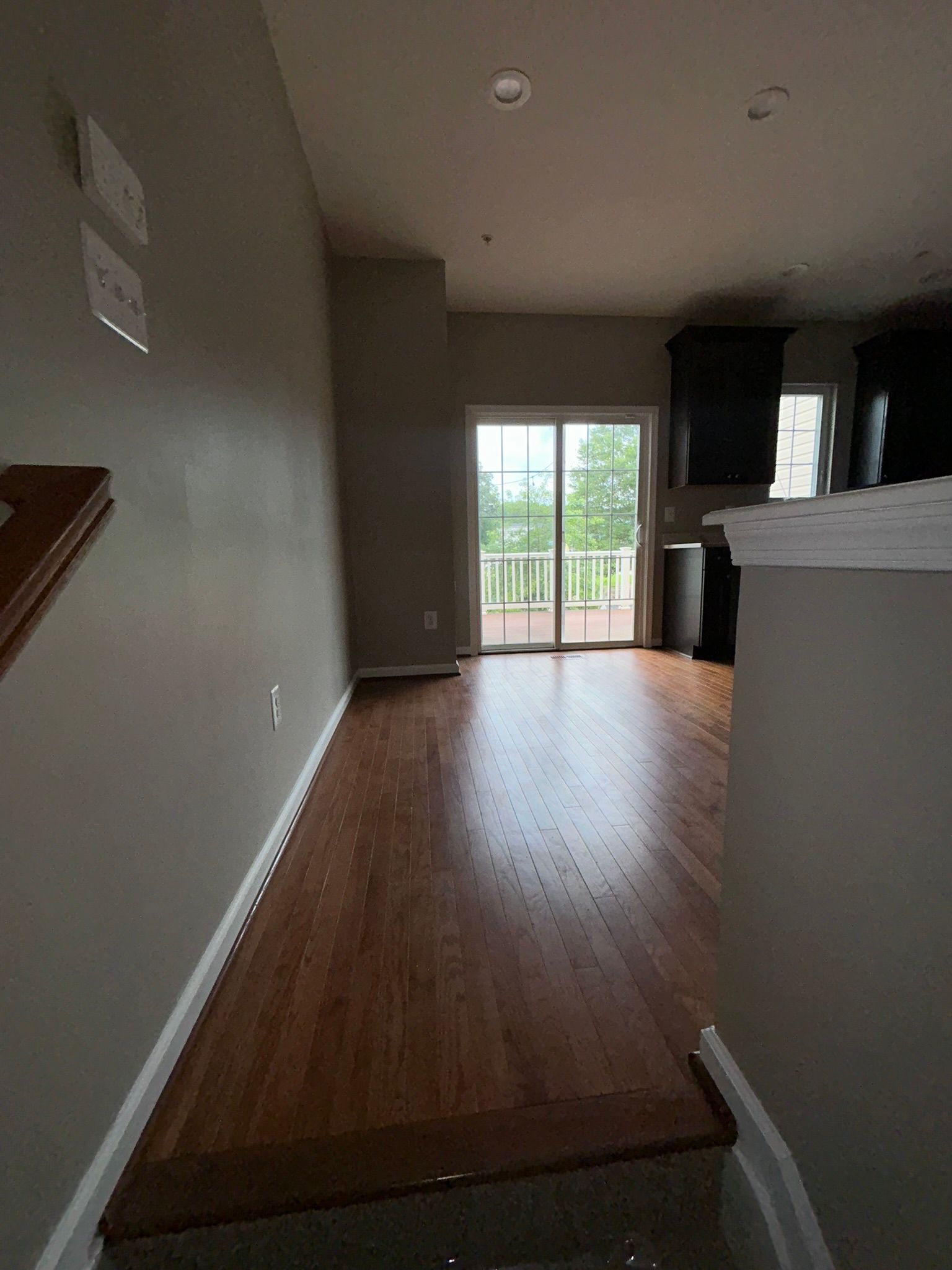 Narrow hallway with wood floors leading to a sliding glass door and outdoor balcony.
