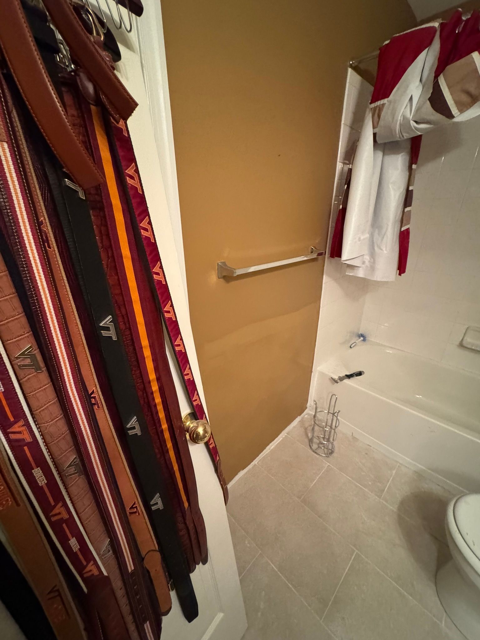 Small bathroom with hanging ties or sashes, grab bar, bathtub, and toilet visible.